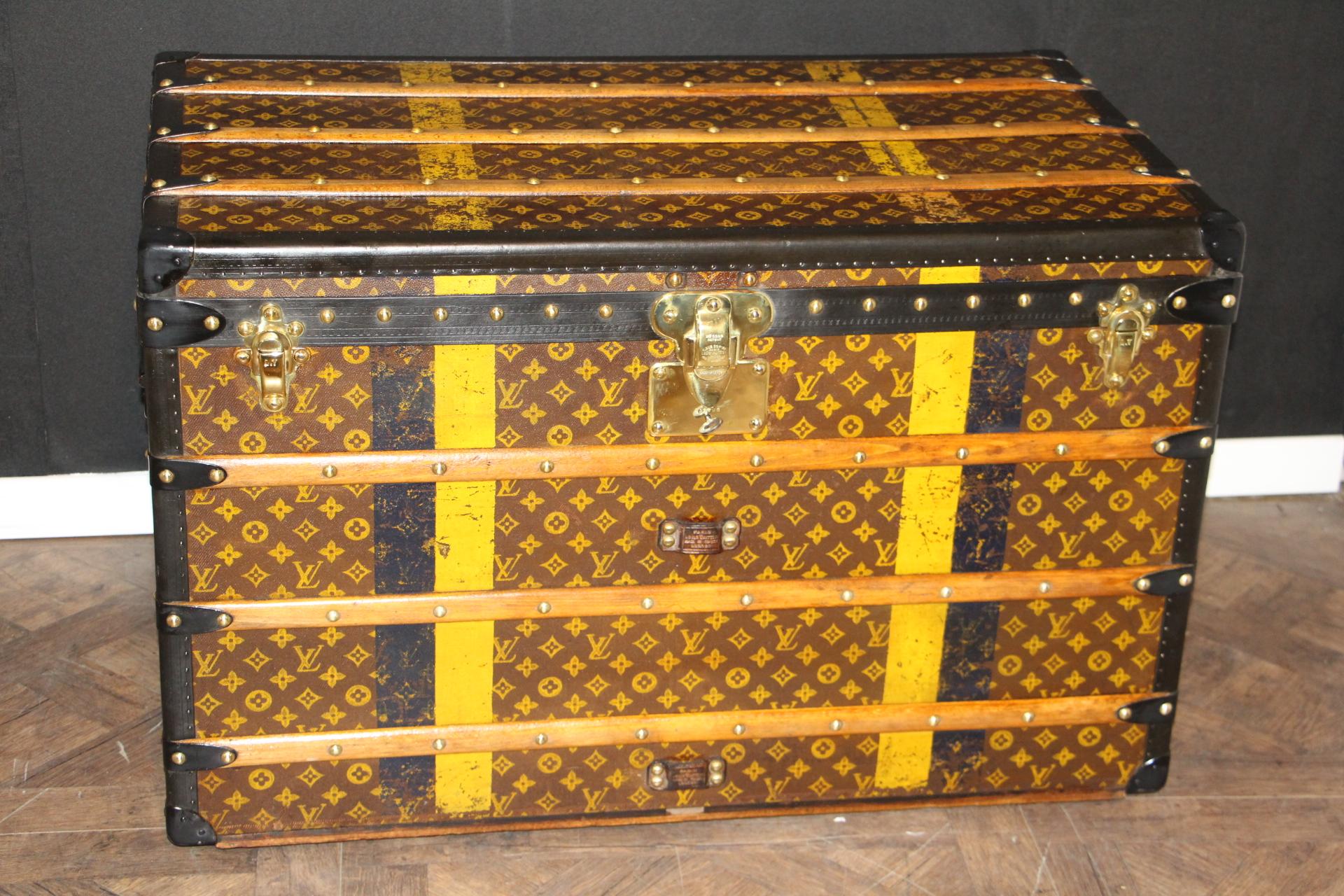 This Louis Vuitton trunk features stenciled canvas, deep black lozine trim, engraved LV black steel side handles, solid brass Louis Vuitton stamped brass lock and clasps as well as Louis Vuitton stamped brass studs. 
Dark blue and yellow customized