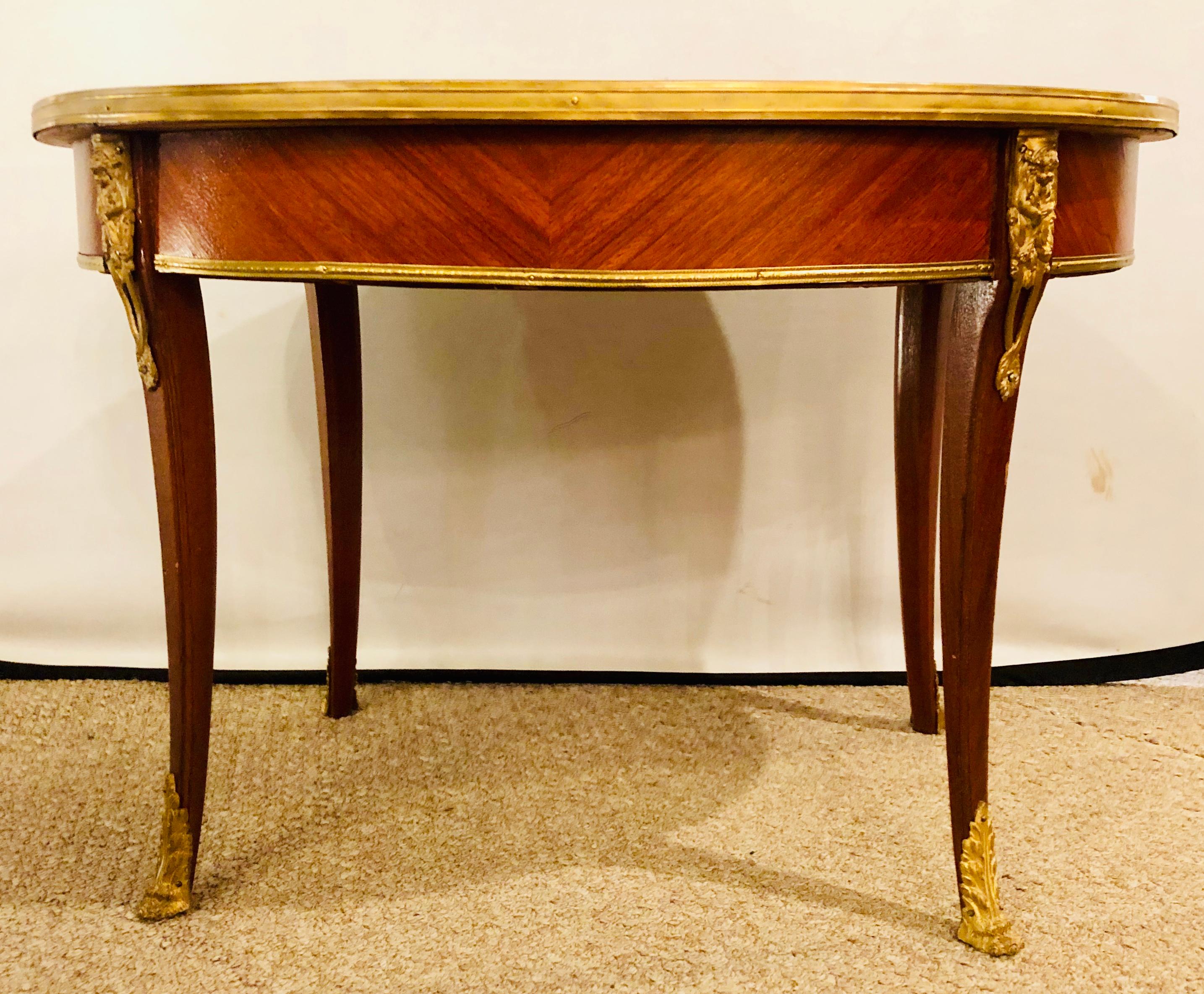 1920s Louis XVI style coffee or low table walnut and marble having an oval form with a bronze framed marble top on curved legs.


Lia.