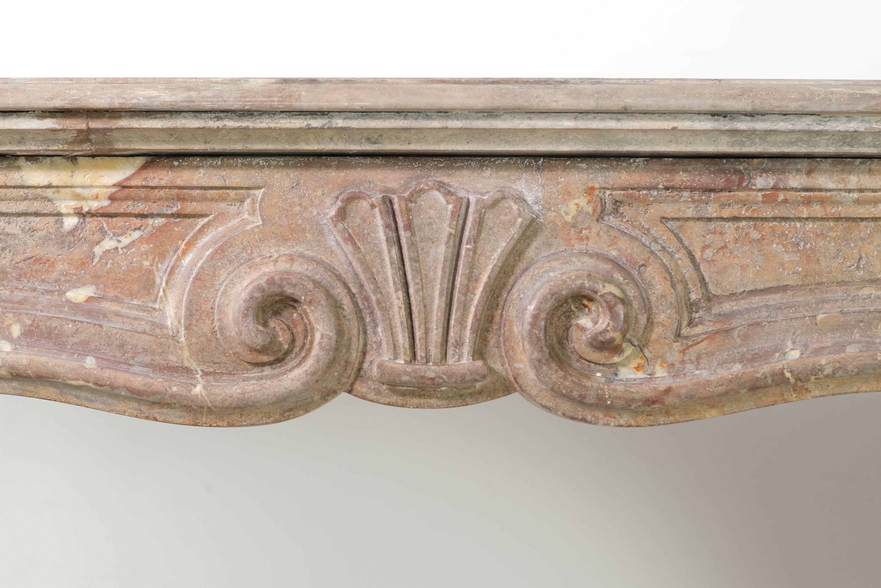 This mantel was recovered from a 1926 well heeled apartment at 950 5th Avenue and East 76th Street on the upper east side of NYC. Hand carved stone featuring various shades of tan, gray, brown, and white. Designed with a scrolled center shell on the