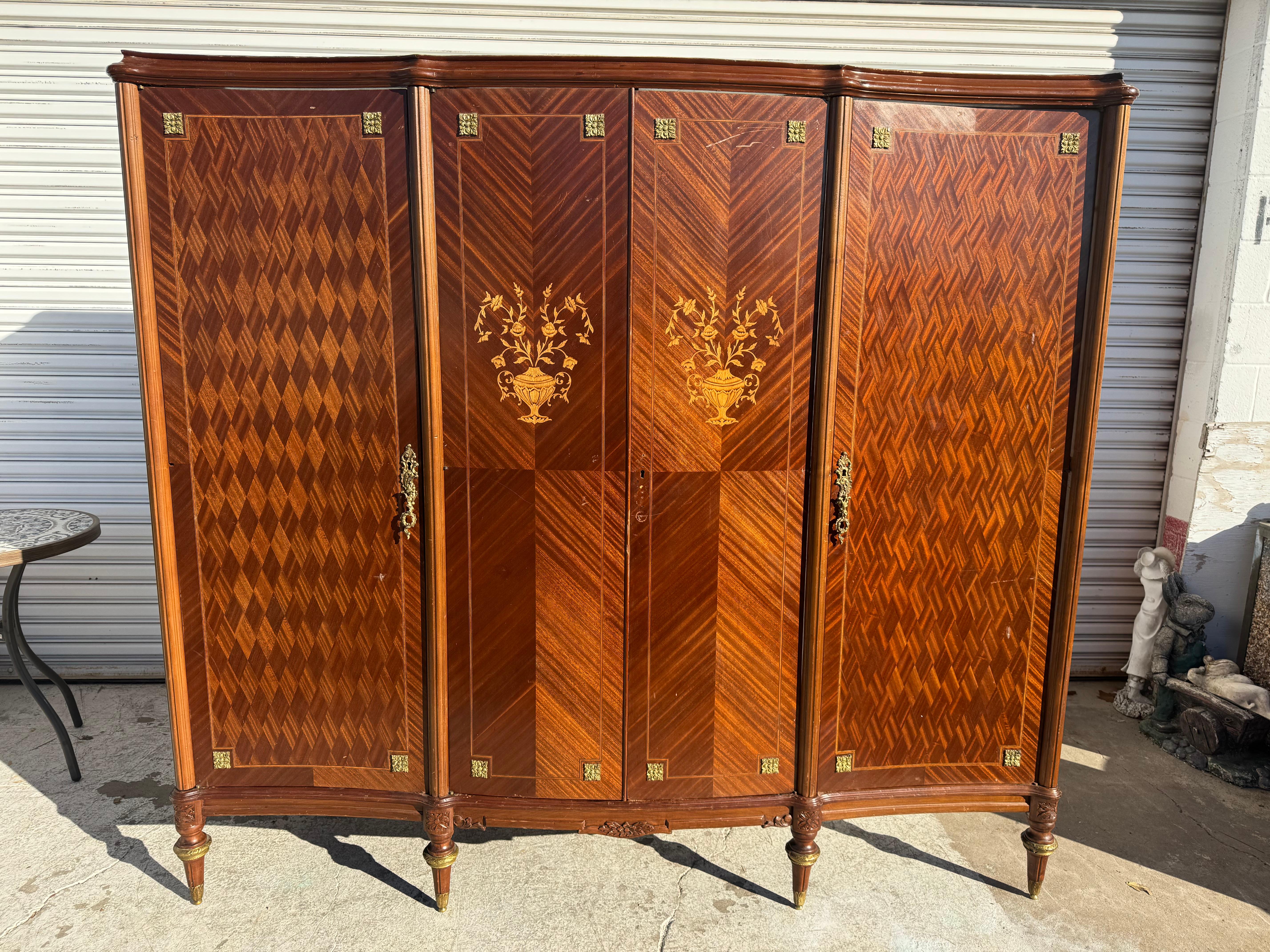 Questo armadio è realizzato in stile Luigi XVI.
È realizzato in noce. Ha delle urne finemente lavorate e botaniche intarsiate sulle porte d'ingresso. Le porte laterali sono realizzate in parquet e hanno tiranti in ottone pesante o in ormolu.