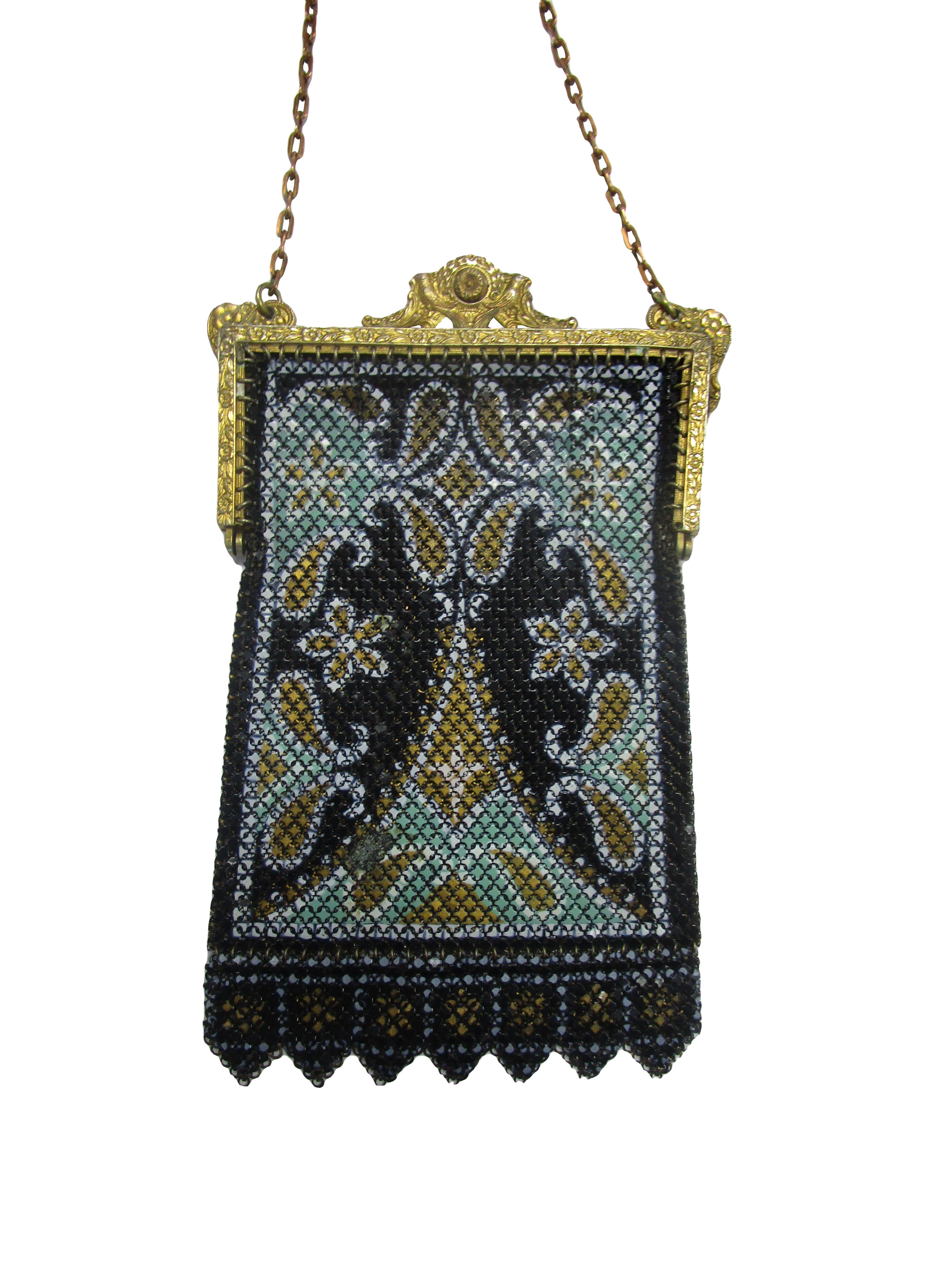
This lovely antique mesh bag from the Mandalian Mfg features a decorative top clasp with floral motifs. The black, gold and mint design on the body of the bag resembles traditional middle eastern style rugs. There is slight aging on the lower left