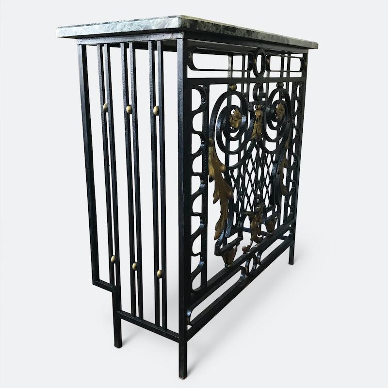A stunning and rare Art Deco French marble and parcel-gilt metal console/ radiator cover. Composing of a rich green marble top and beautifully crafted wrought iron work of serpentine scrolls and foliate swags painted in black and highlighted with