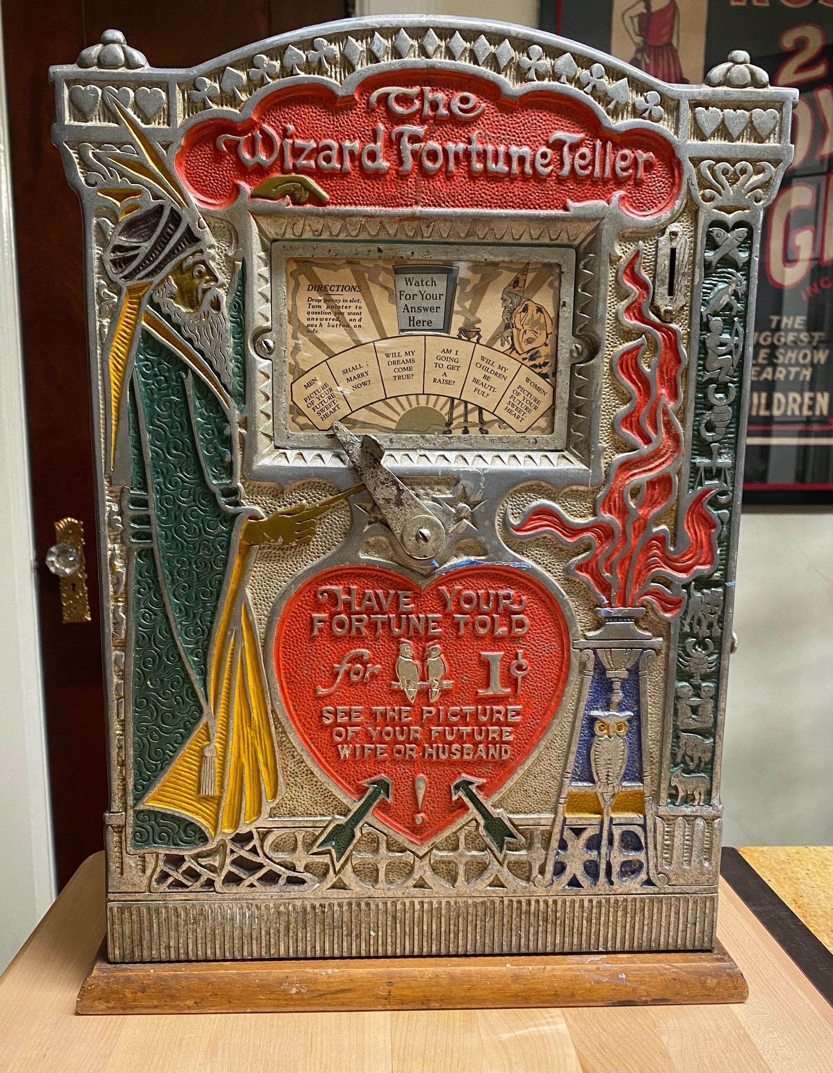 1920s Mills 1 cent Wizard Fortune Teller, Chicago, Mills Novelty Co..Tabletop fortune telling machine in a wooden cabinet. window with working question lever. coin slot and button on side.which activates inner reel that displays humorous 
