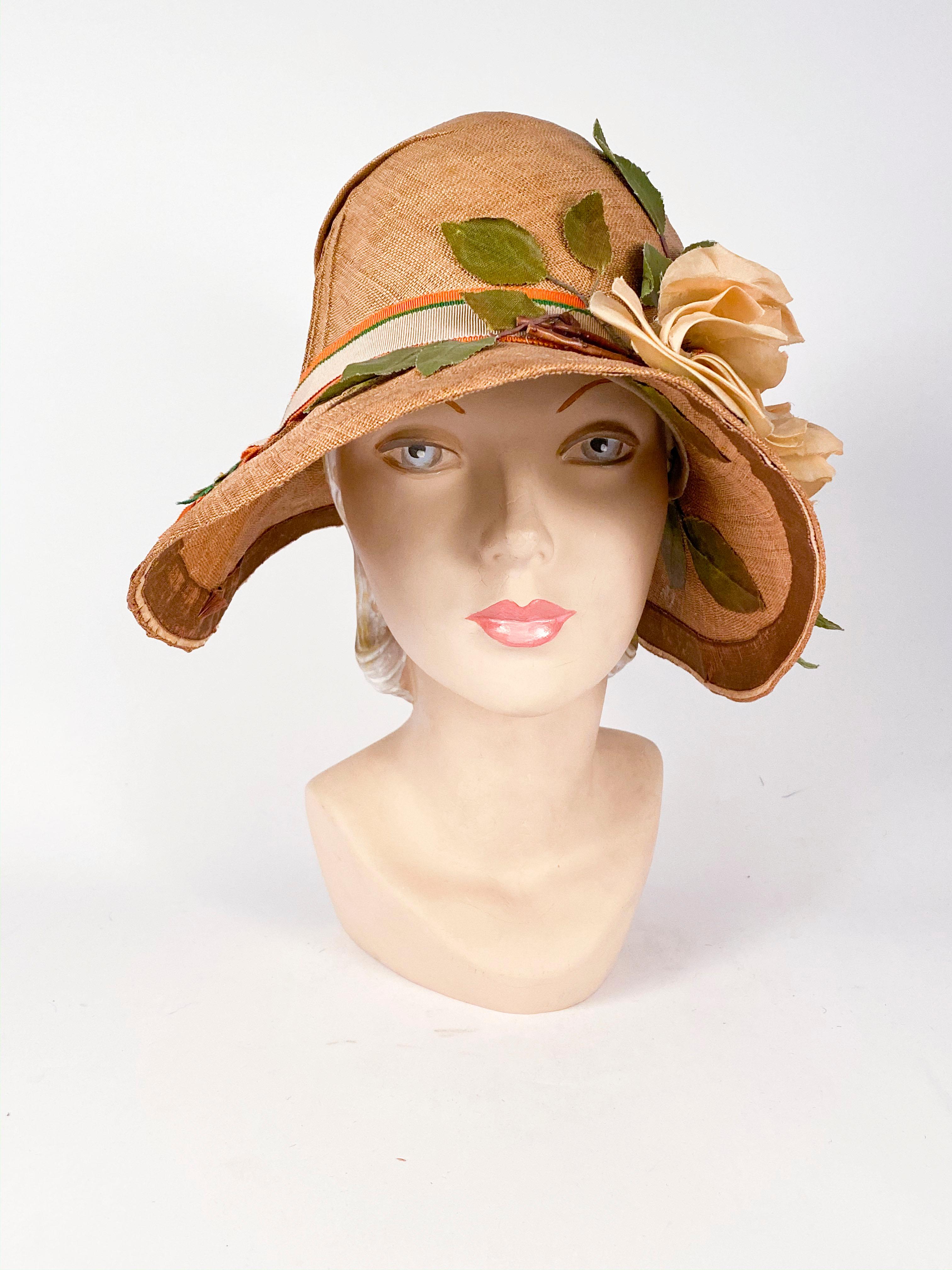 1920s hand woven natural colored panama day cloche with handmade silk flowers, three-toned (orange, green, and beige) grow-grain band, foliage, and pin pleat accents.

