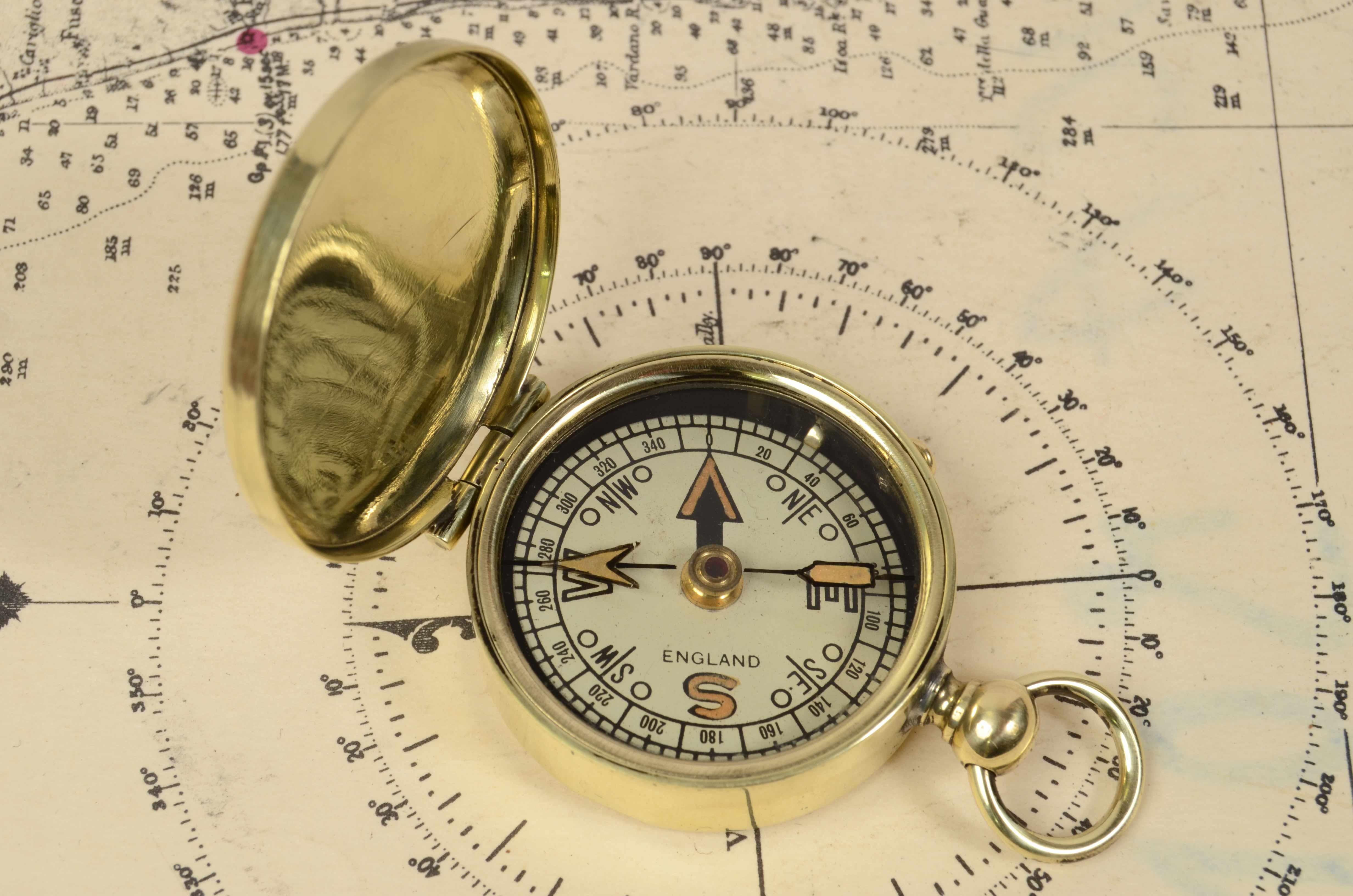 Nautical pocket compass made of turned brass, 1920s English manufacture. 
The compass is complete with cover, compass card lock and chain ring. 
Eight winds compass card on paper complete with goniometric circle. 
In excellent condition, fully