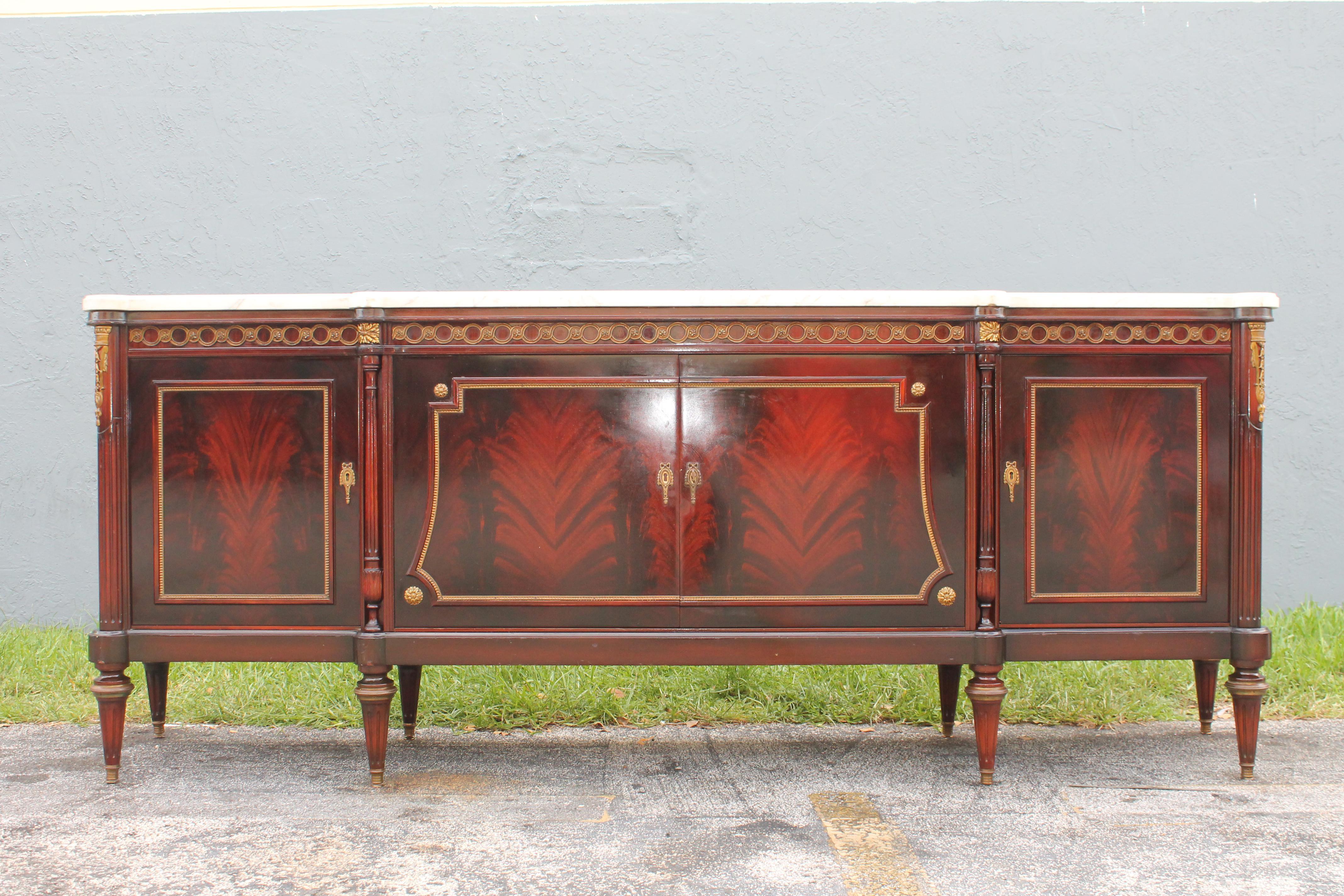 Spectacular 1920's French Neoclassical style Buffet/ Sideboard/ Credenza/ Dry B ar. Flame Mahogany with the most beautiful marble top. Opens to reveal drawer storage/ shelf storage and a dry bar on the right which has hidden lights. The adornment is
