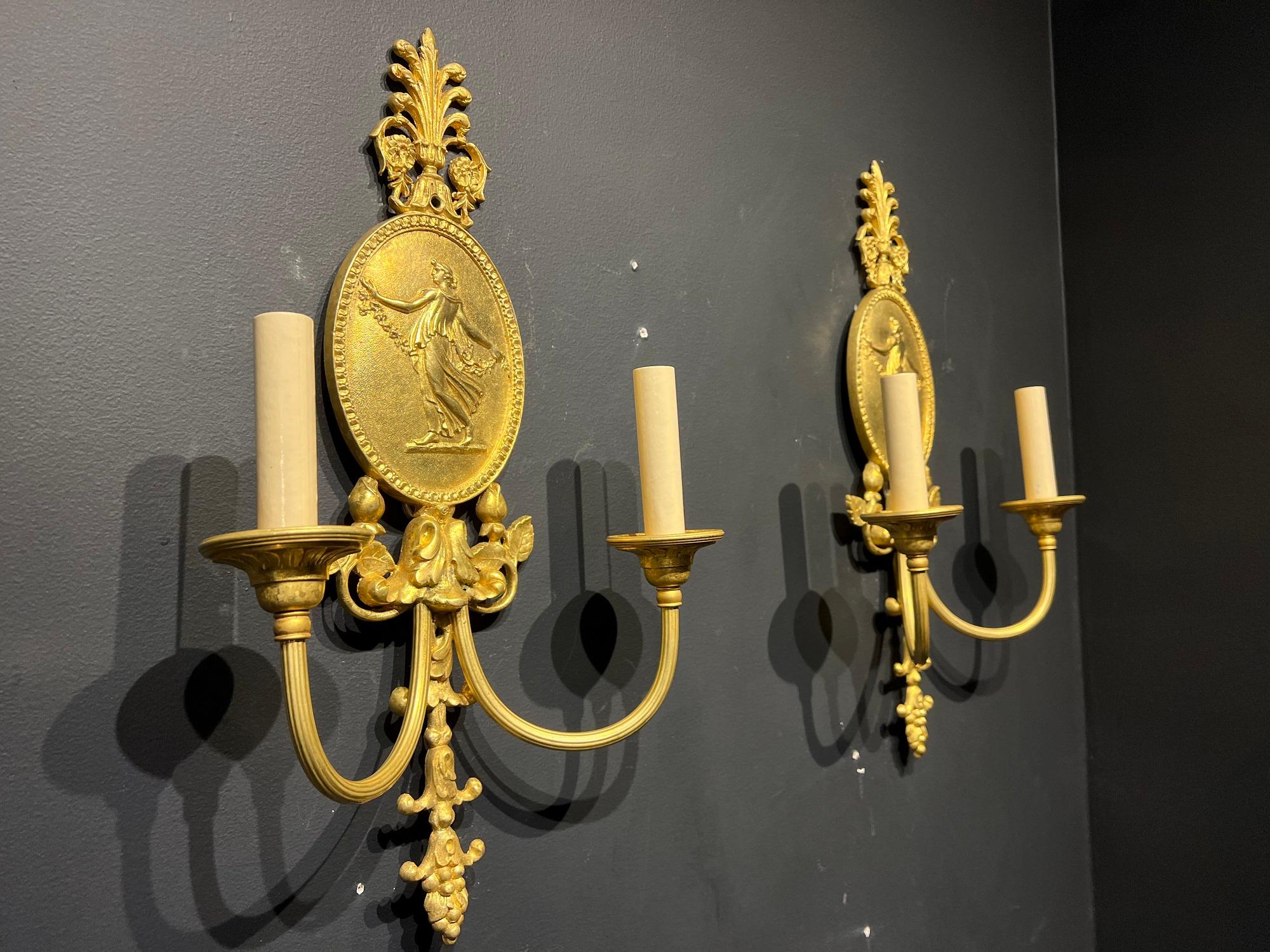 Un par de apliques de bronce dorado de estilo neoclásico Caldwell de hacia 1920 con camafeos y dos luces