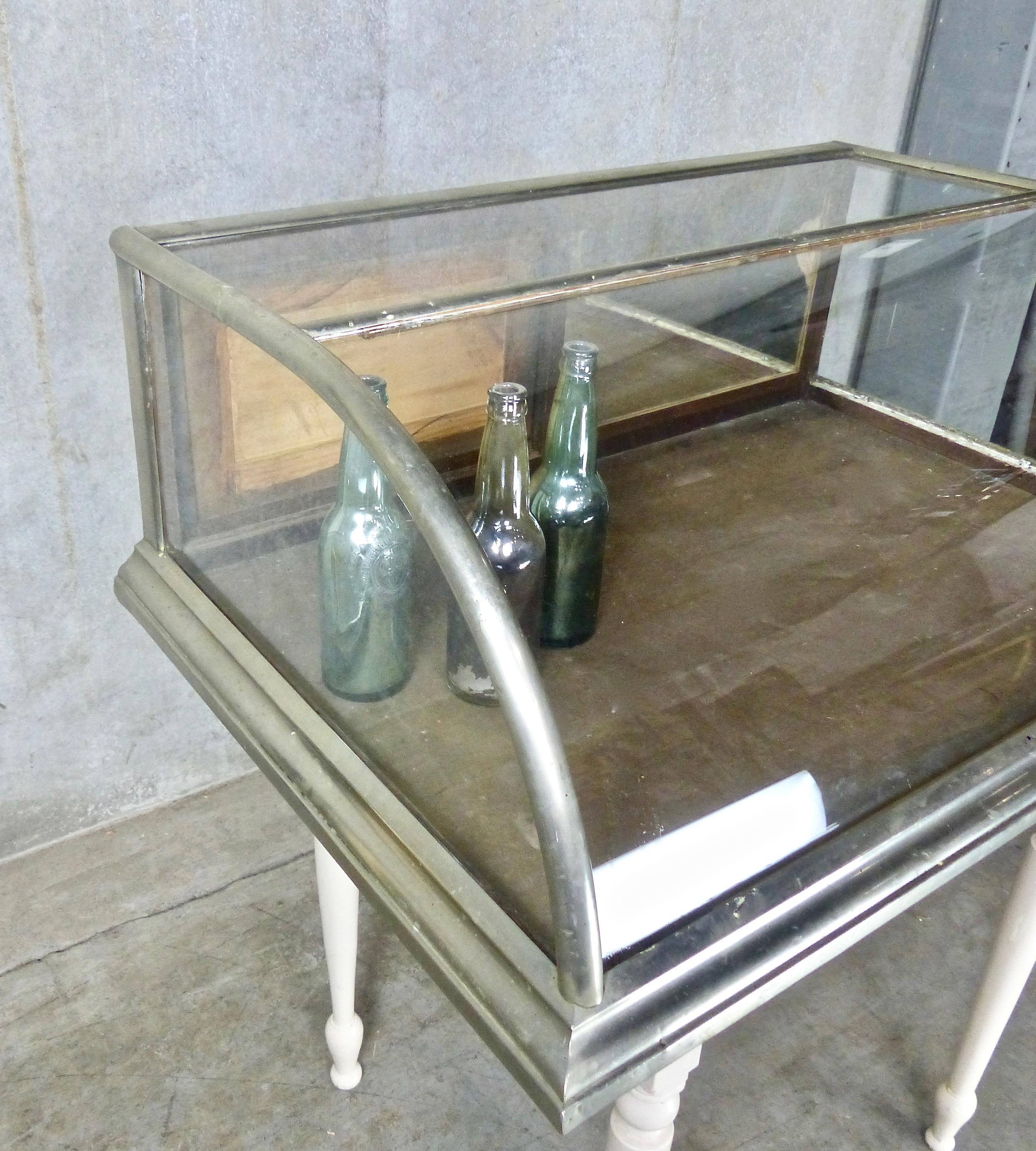 A rare, compact-sized mercantile display case in original curved glass by Dominion Showcase Works of Toronto. Designed as a countertop display/merchandising case, it features sliding wooden doors in the rear.
Dimensions 12” H x 33” W x 24”