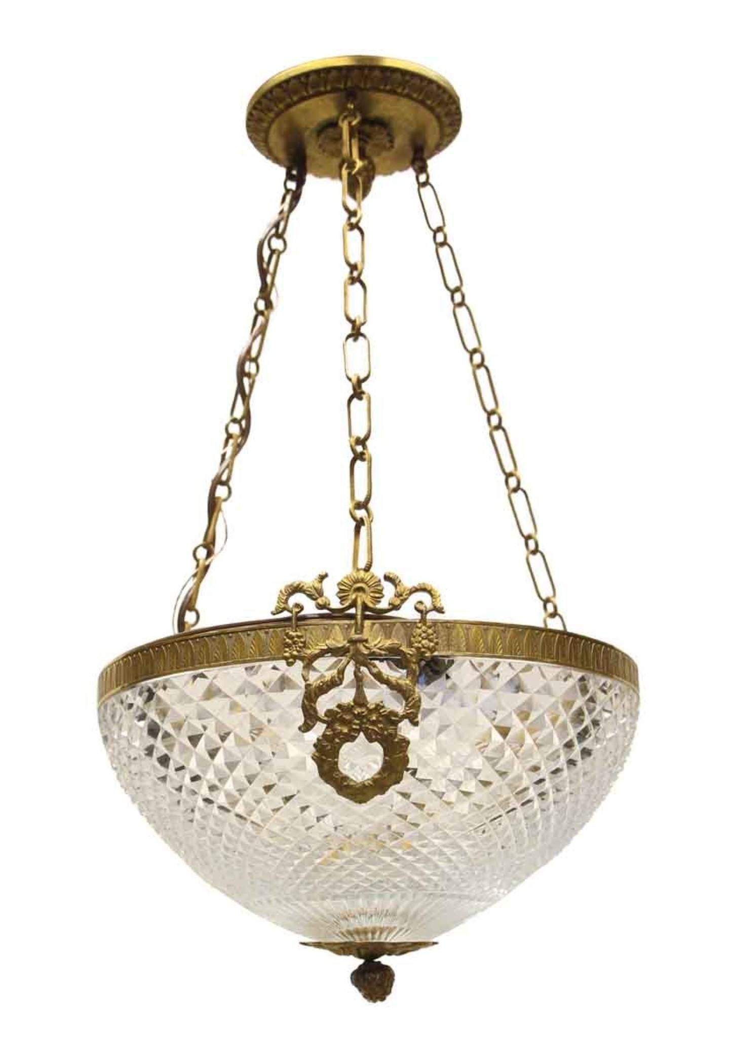 1920s gold gilt brass and clear cut crystal dish pendant light with decorative wreath and bow detail. Three candelabra sockets are inside the bowl. This was retrieved from the 36th floor of the Waldorf Astoria towers. It has been fully restored.