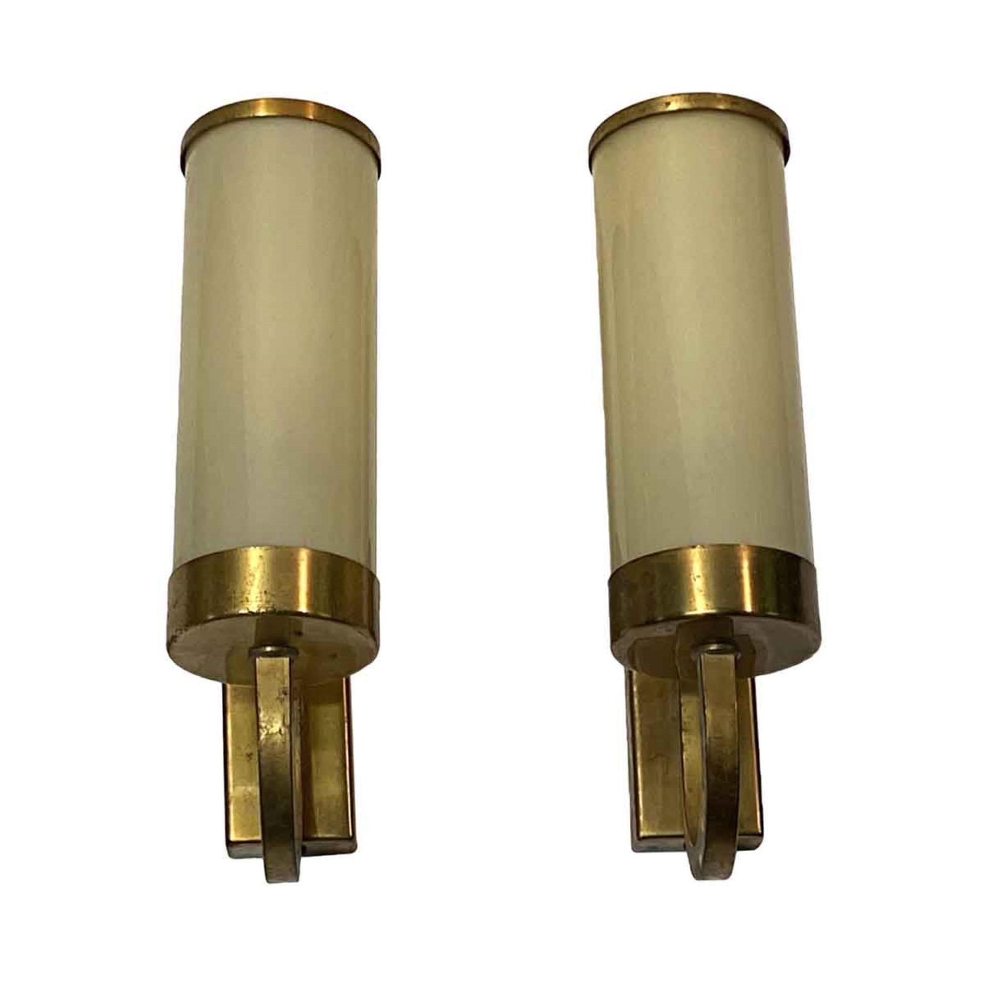 Brushed brass over steel original cylinder shaped sconces with tan glass from 1920s. Priced as a pair. Price includes restoration.