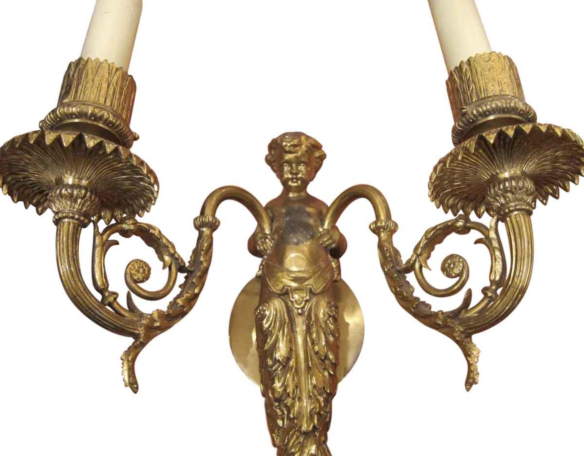 This pair of elegant bronze double arm wall sconces are from the early 1920s. Featuring putti details in center. Finely cast. Sold as a pair. This can be seen at our 400 Gilligan St location in Scranton. PA.