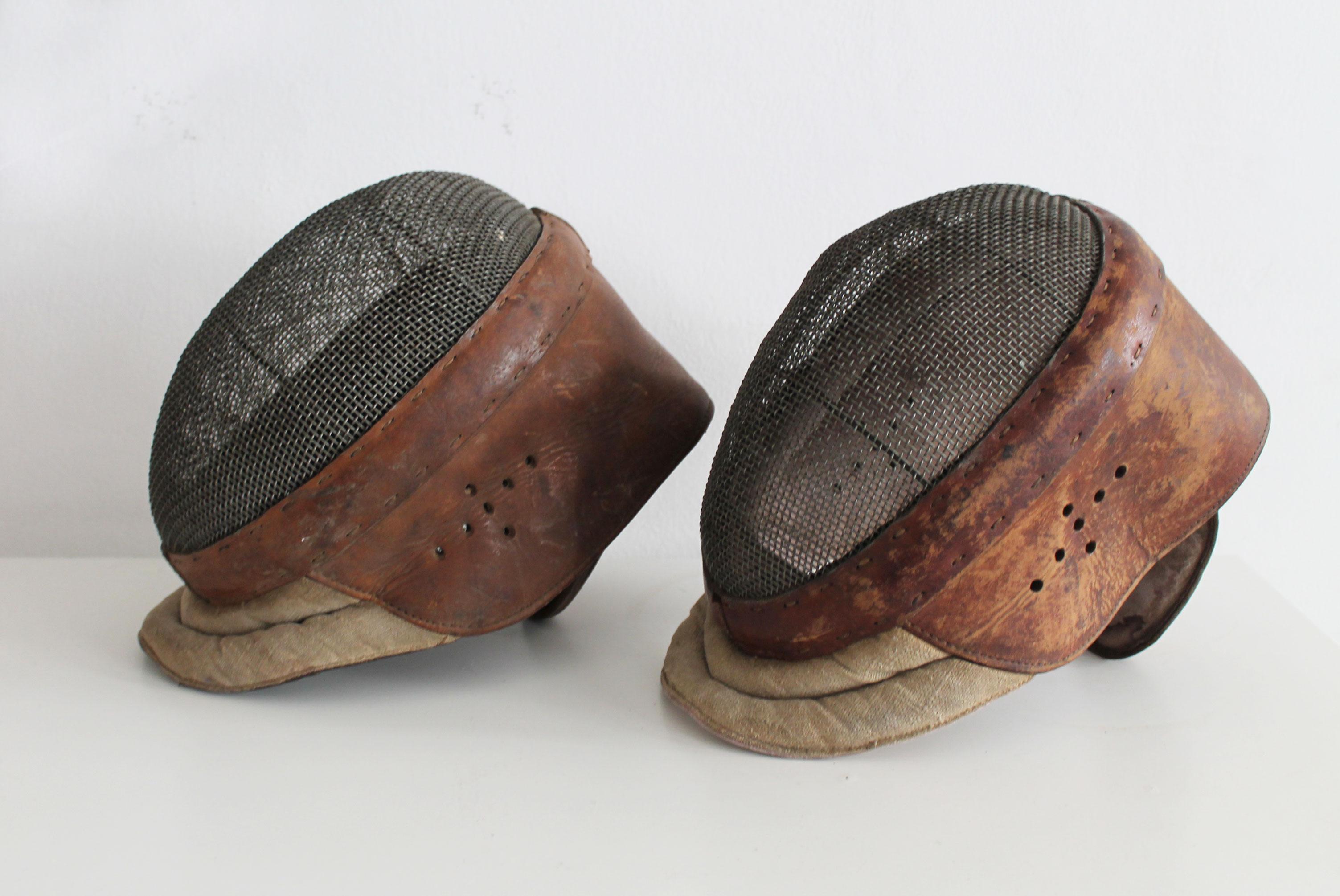 This is an original par of fencing mask believed to be produced in France in the 1920's.

Both masks are made of rich brown coloured leather with a hard steel mash for protecting the face and thick light brown fabric to protect the neck. The leather