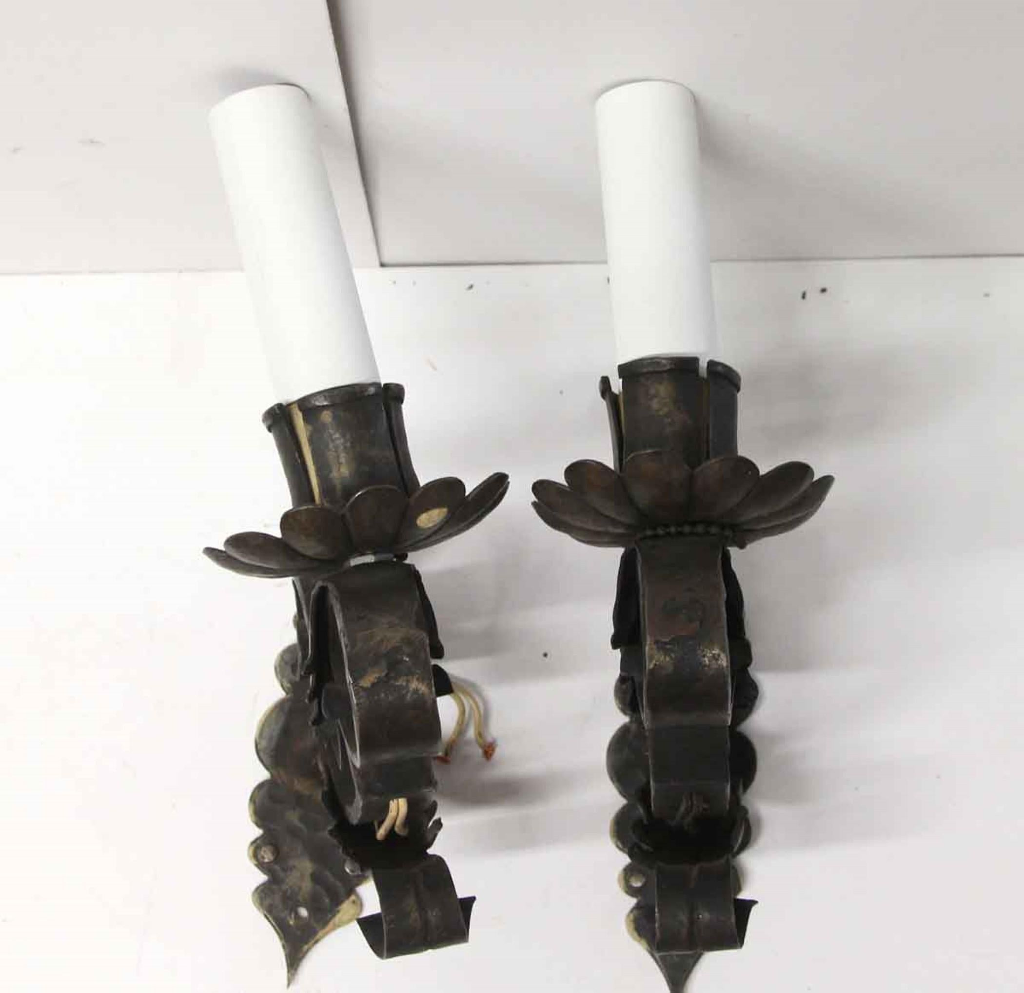 Offered is a pair of cast iron sconces from the 1920s. They are designed with a single candlestick arm, scrolls, the acanthus leaf design, and a flower cup bobeche. Priced as a pair. This can be seen at our 400 Gilligan St location in Scranton, PA.