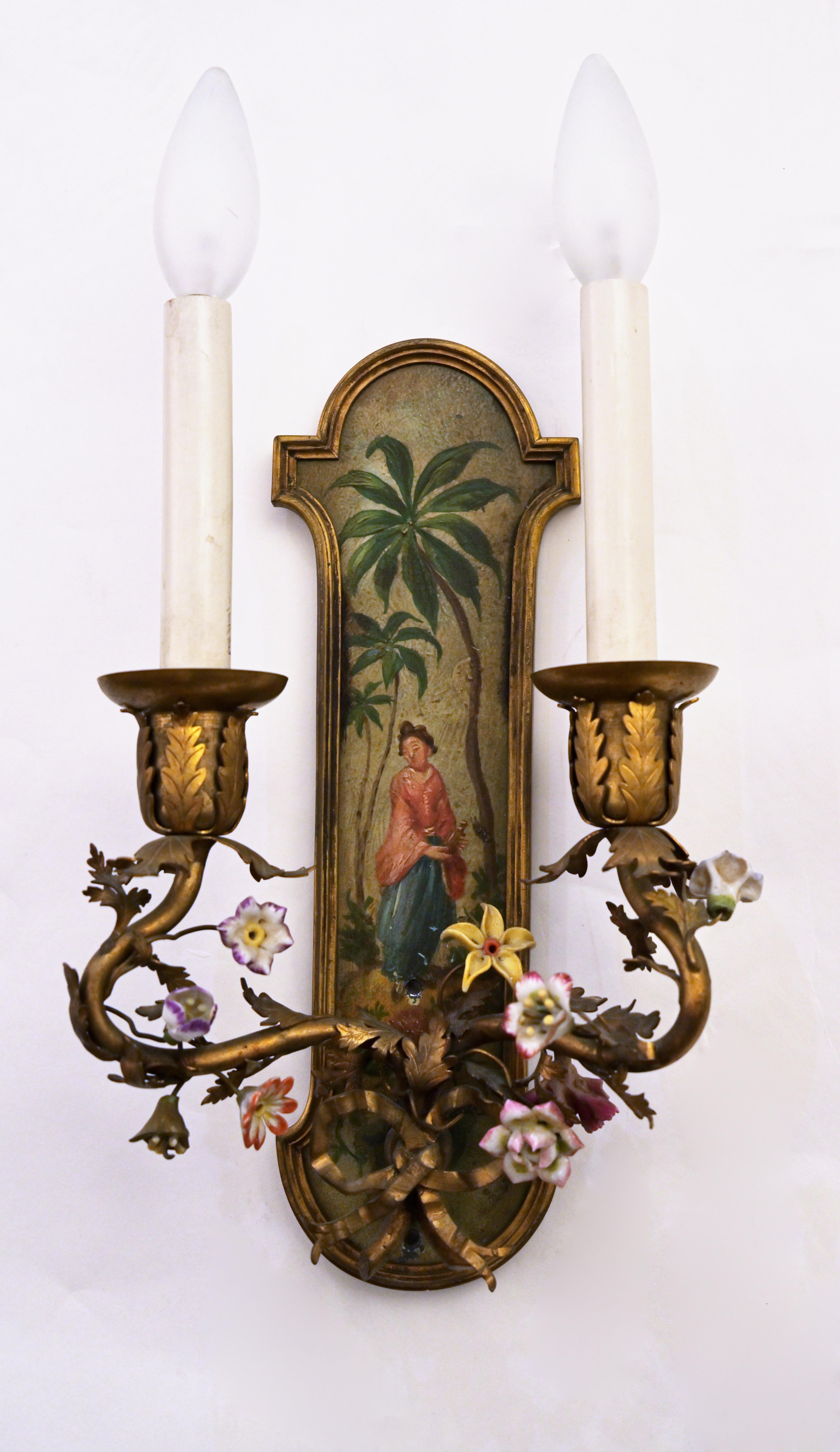 Pair of French Louis XVth style sconces, the shaped metal backplate with bronze edge having hand painted Chinese inspired figures and landscape. Arms are decorated with porcelain flowers. Circa 1920. Includes UL wiring.