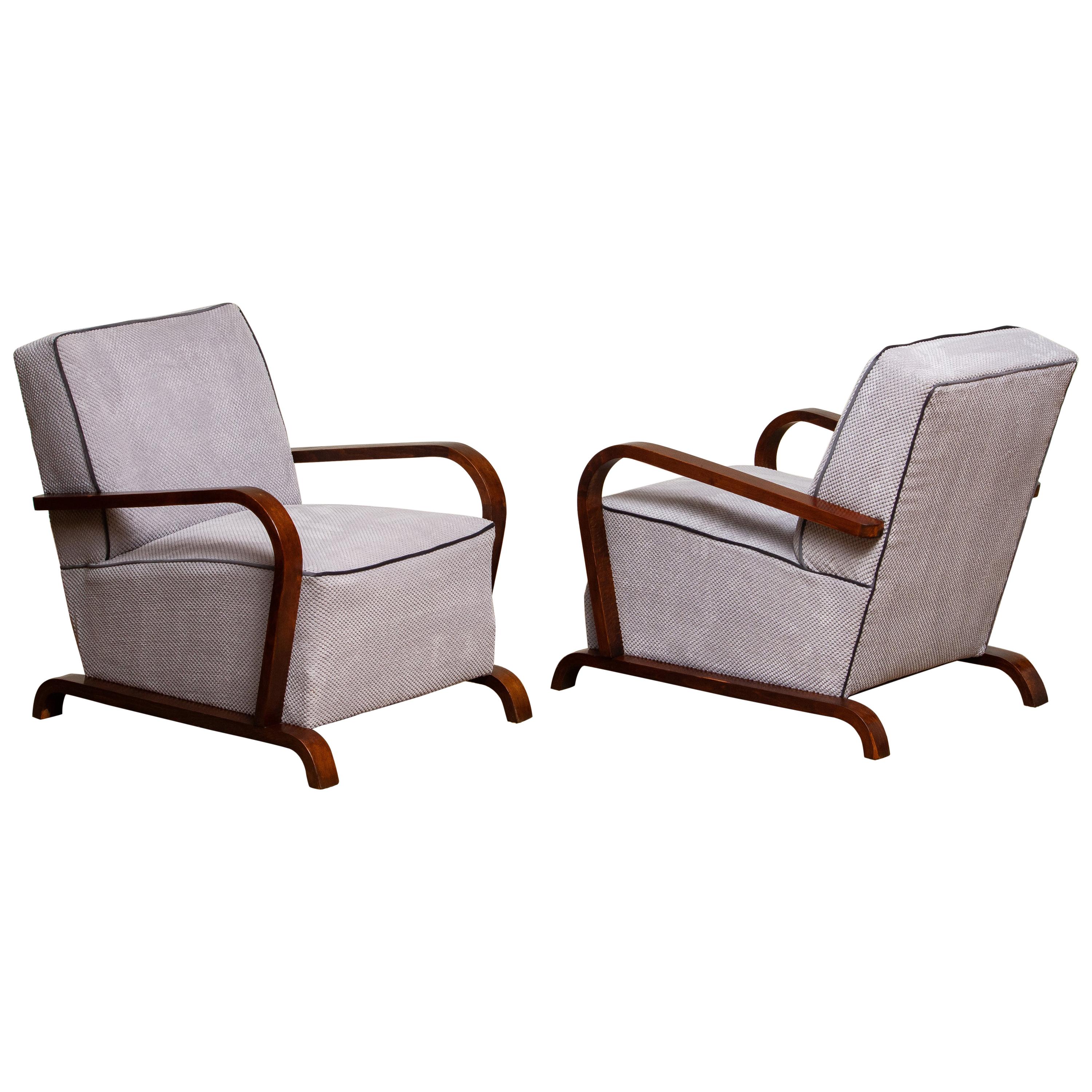 Beautiful set of two Swedish original Art Deco arm, club or lounge club chairs in grey senile fabric with black piping in combination with mahogany colored beech stands and armrests.
The chairs has been restored and newly upholstered, keeping all