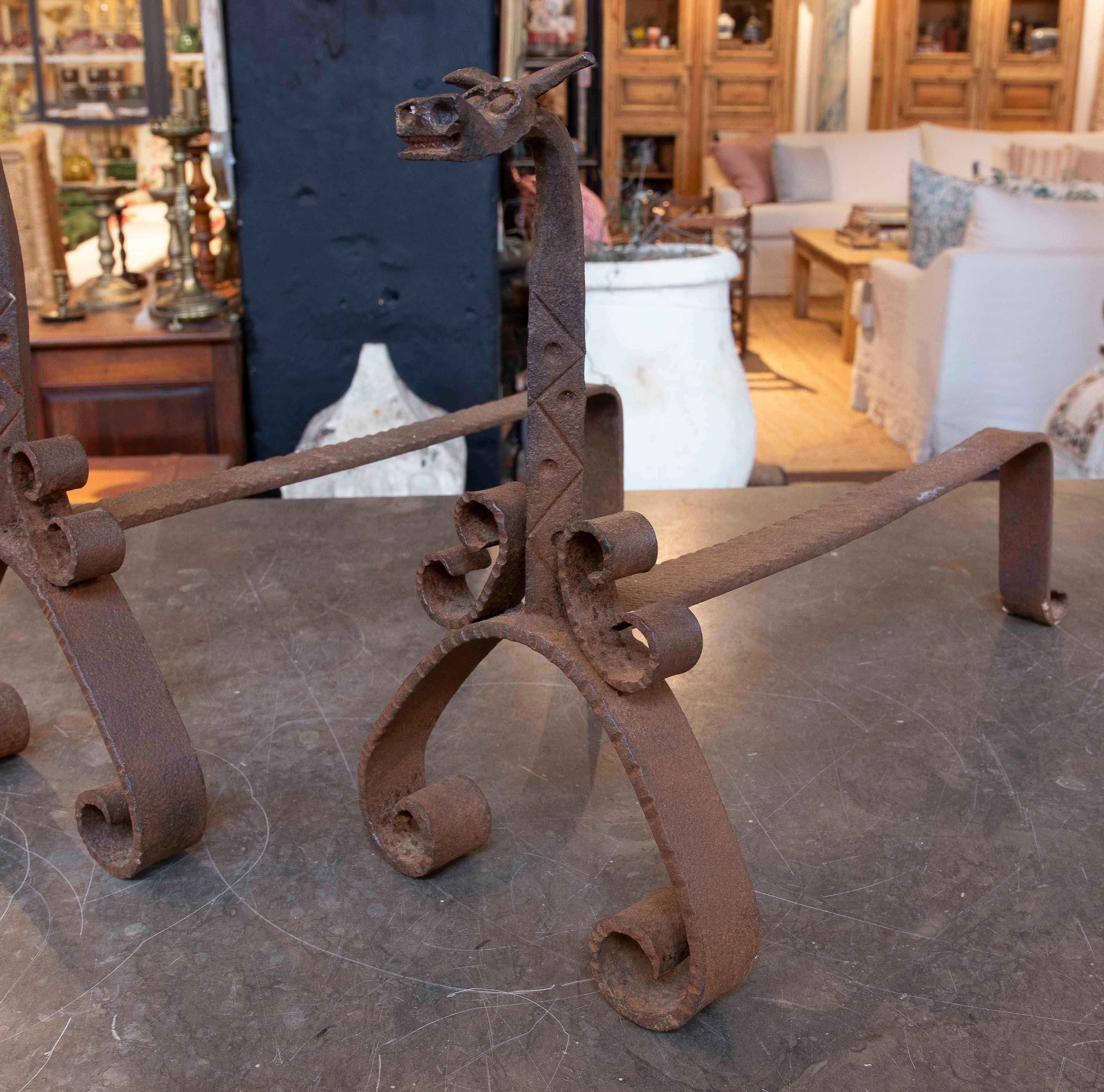 Distinta coppia di spugnole in ferro battuto, disegnate con teste di drago dettagliate sulla parte superiore e basi a spirale. Questi pezzi combinano funzionalità e design artistico, rendendoli ideali per contenere la legna da ardere nel camino e