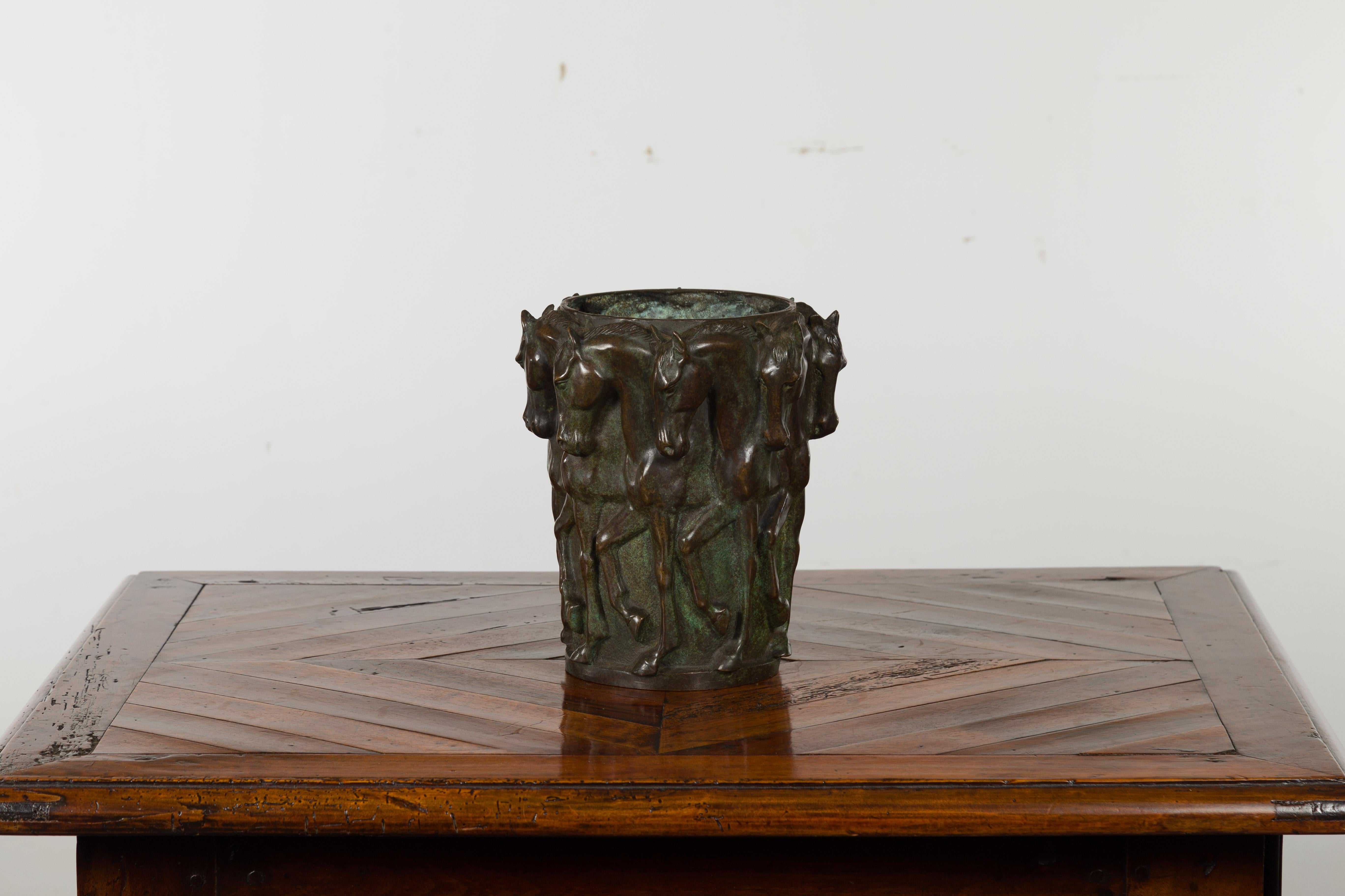A bronze vase from the early 20th century, with frieze of passing horses. Created during the first quarter of the 20th century, this patinated bronze vase draws our attention with its frieze of passing horses cast in high relief. Placed anywhere in