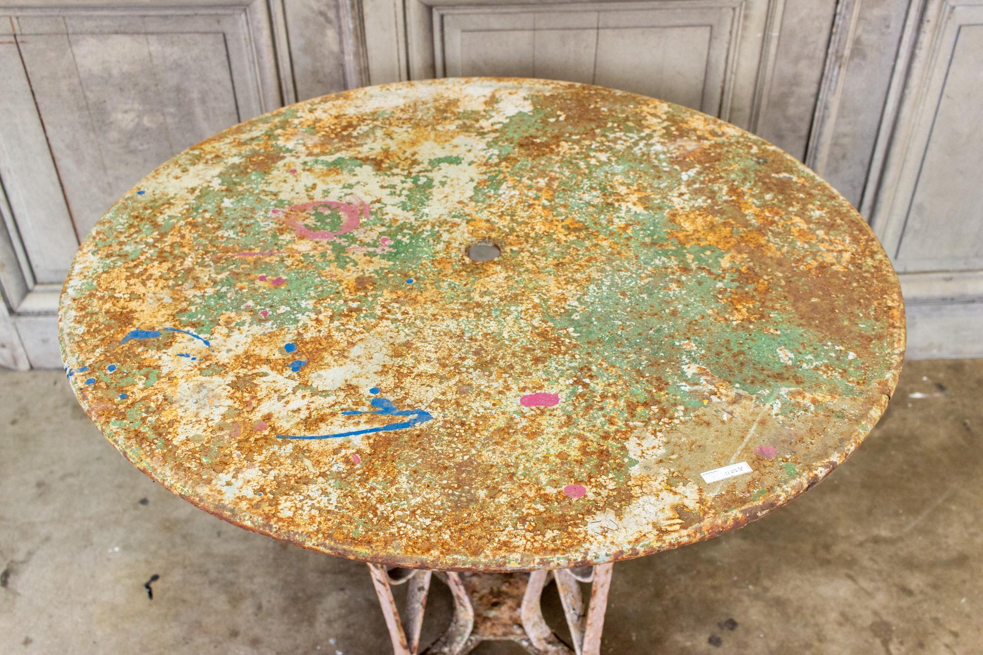 This stunning antique French garden table has fabulous scroll work in the base and an incredible distressed painted finish. The round top also features an opening at the top for drainage or an umbrella. The painted surface has tones of dusty pink,
