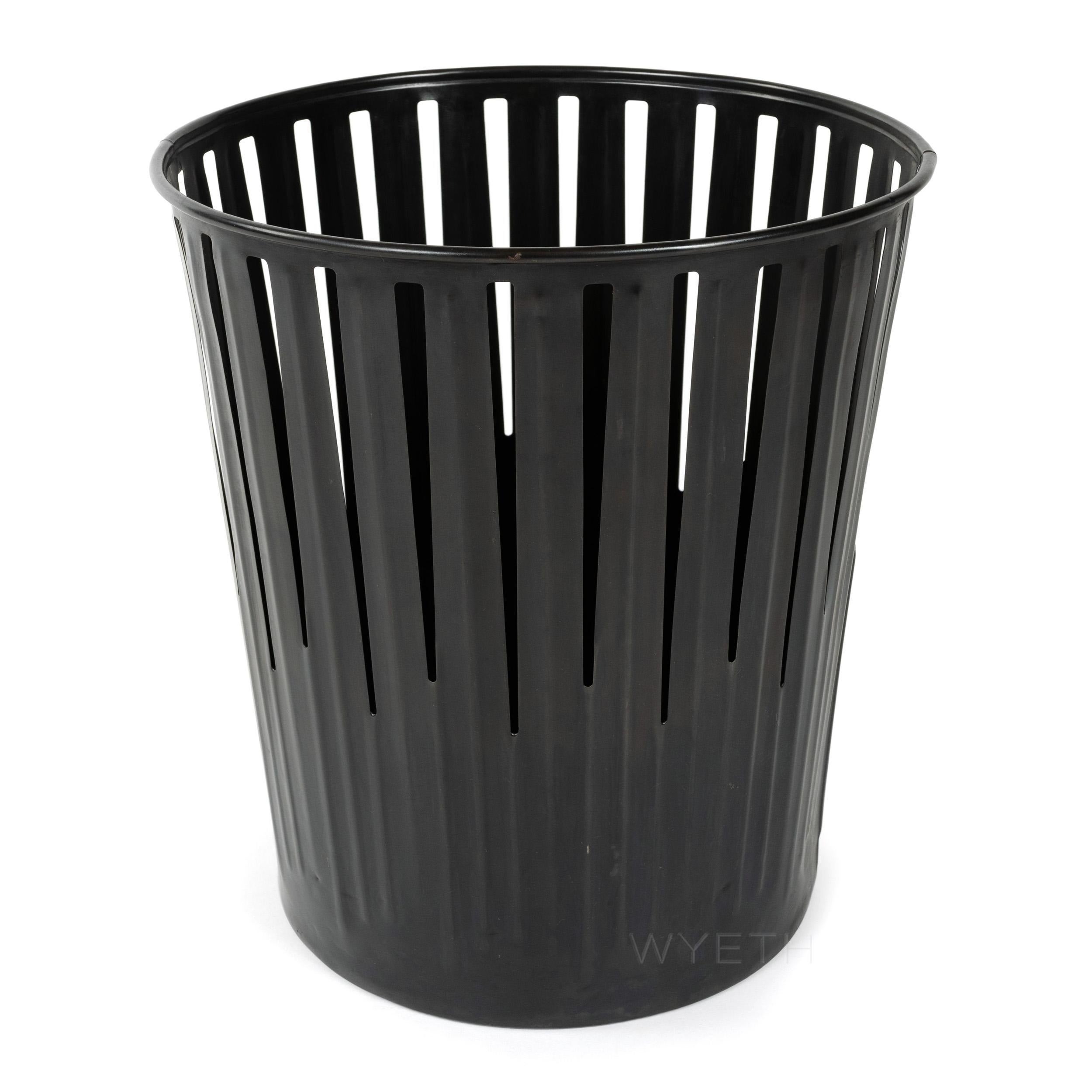 A patinated steel Industrial waste basket having long triangular cutouts and a rolled rim.