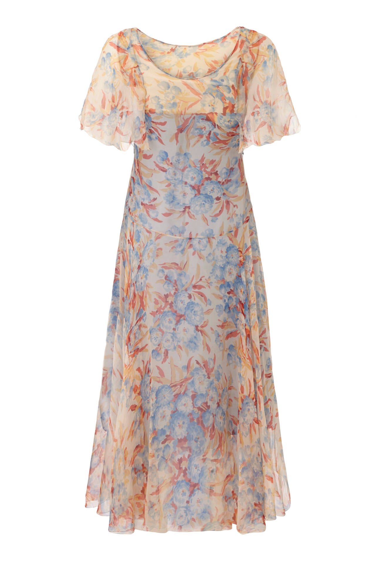 This enchanting 1920s silk chiffon floral print dress is delightfully feminine and in absolutely beautiful condition for a piece of this era. The dress has a scoop neck at both front and reverse , and features cape style sleeves with scalloped edge