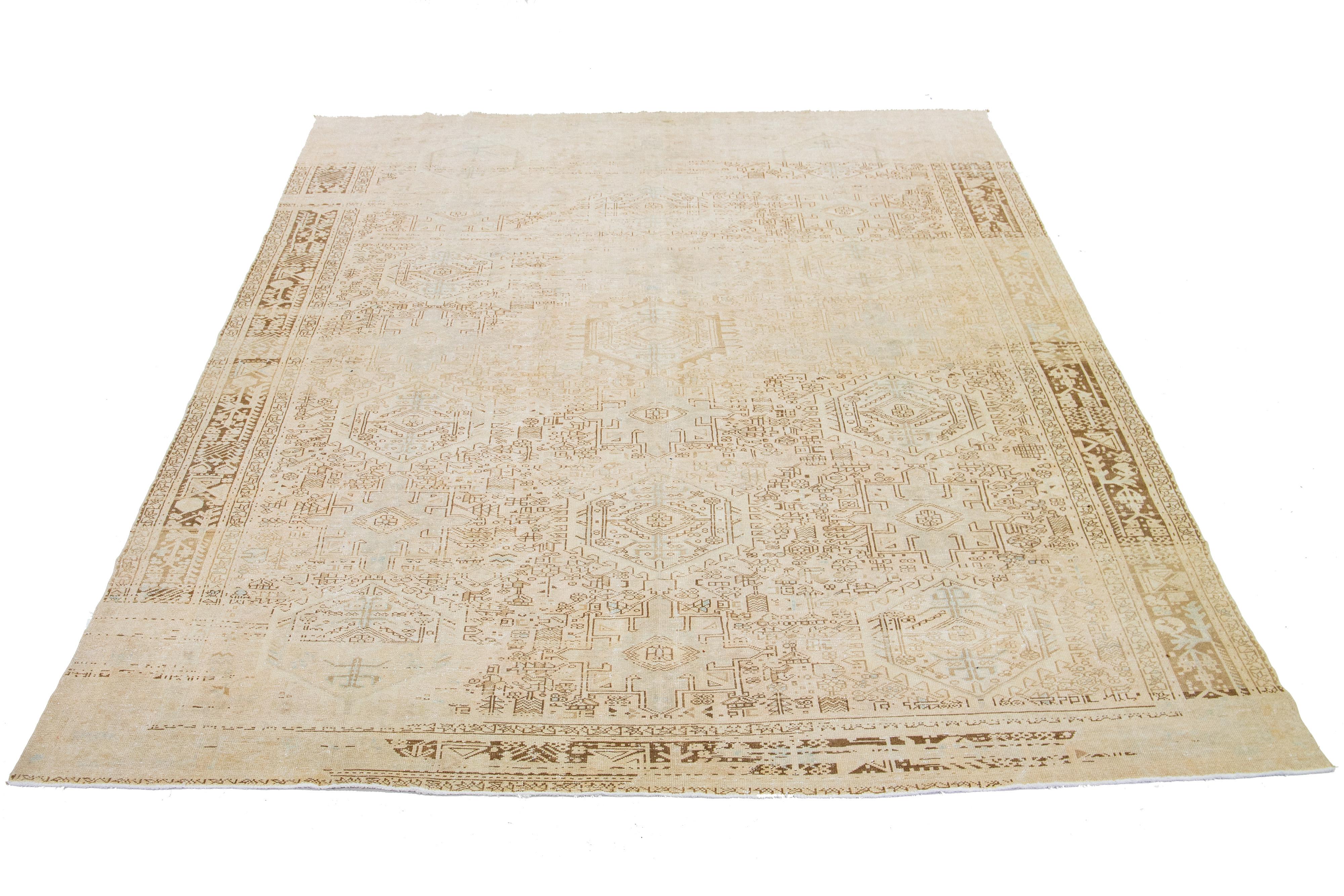 Dieser antike persische Heriz-Teppich besticht durch sein beeindruckendes Medaillonmuster und seine handgeknüpfte Wollkonstruktion. Das beigefarbene Feld bildet den Hintergrund für das auffällige geometrische Blumenmuster, das in Blau- und