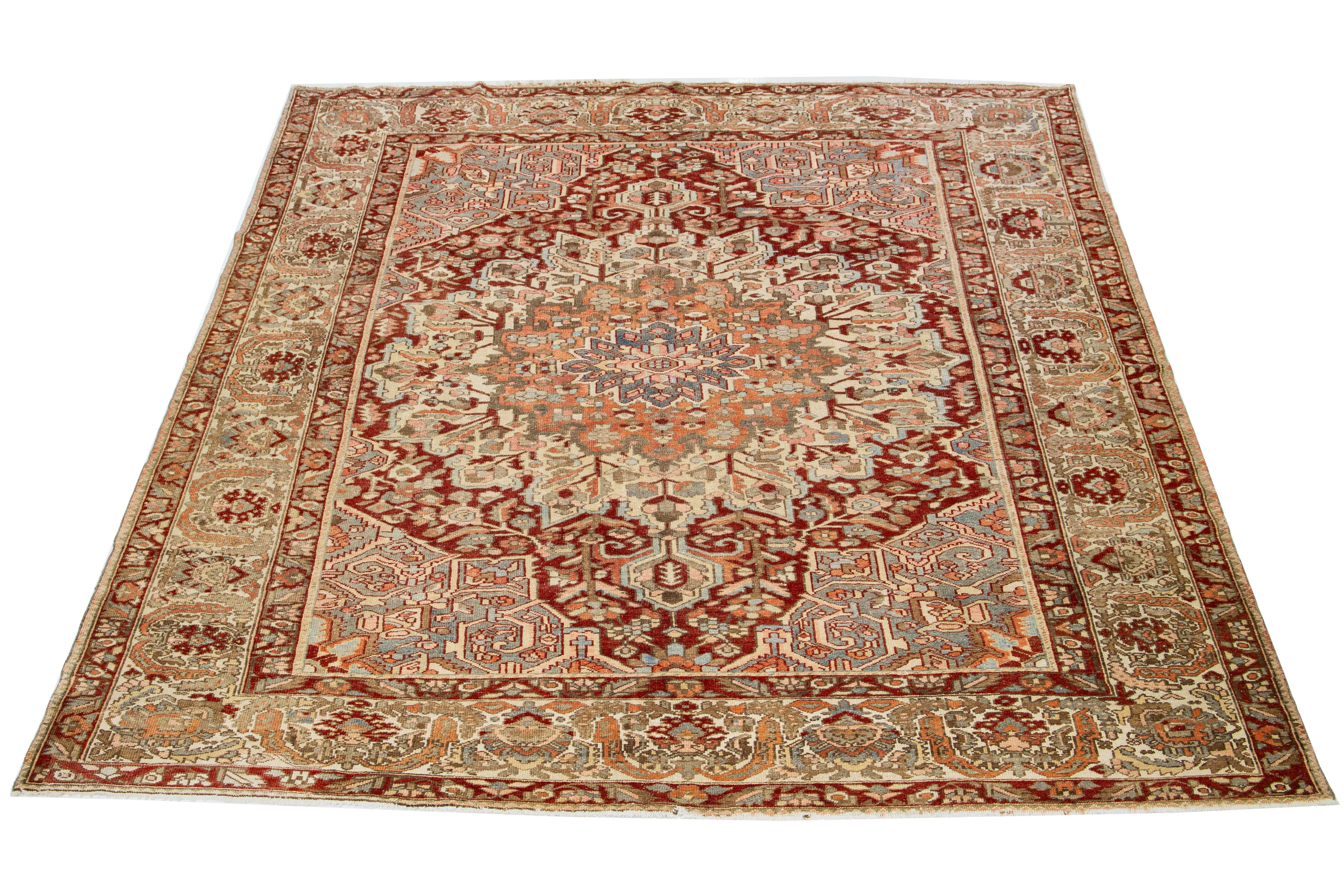 Beautiful room size 1920s Antique Bakhtiari hand-knotted wool rug with a rust color field. This Persian piece has blue, beige, orange, and pink in a classic rosette Motif.

This rug measures 10'1