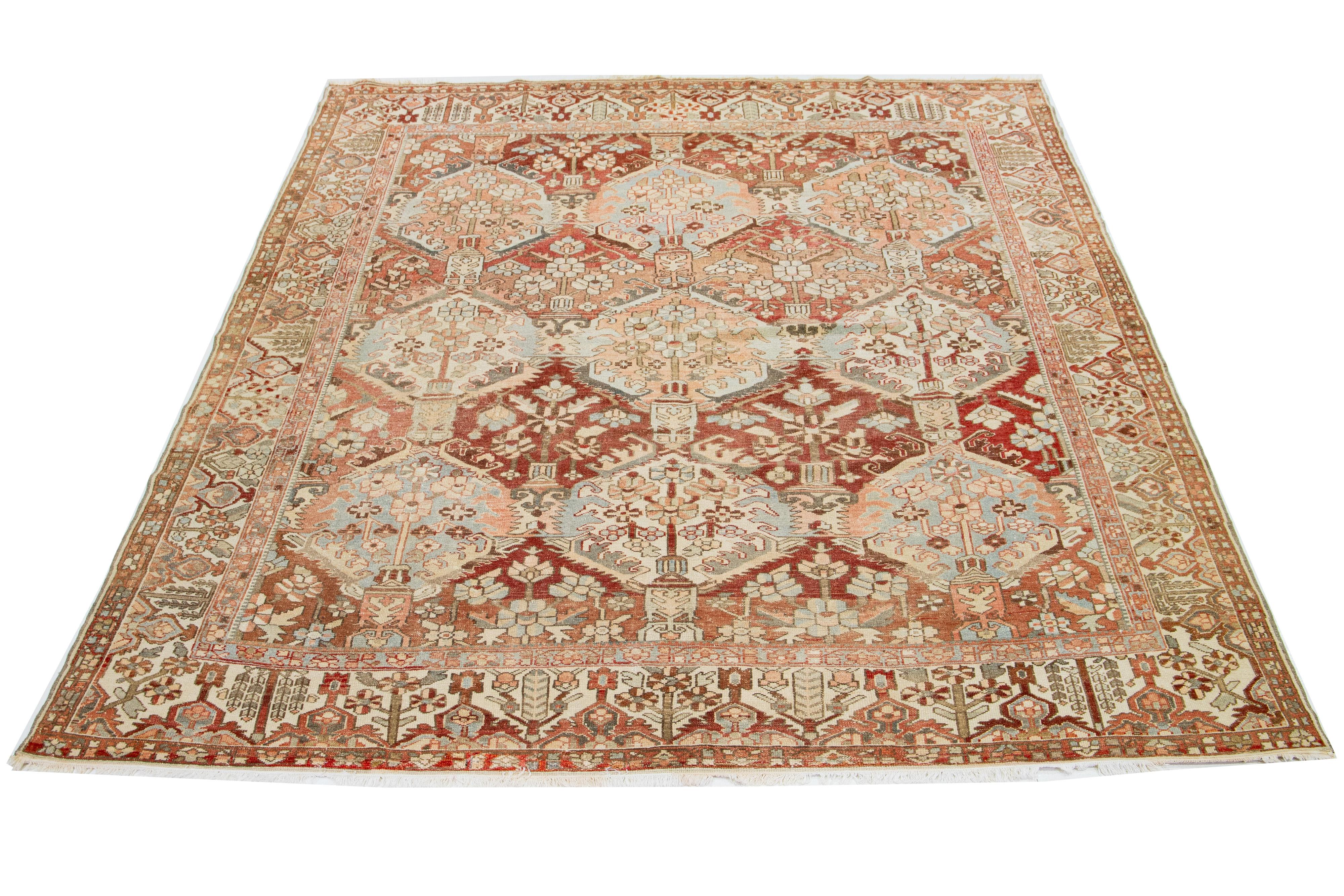 This is a beautiful Antique Bakhtiari hand-knotted wool rug featuring a red-rust color field. It showcases a classic Persian design with blue, beige, and peach floral colors.

This rug measures 10'5