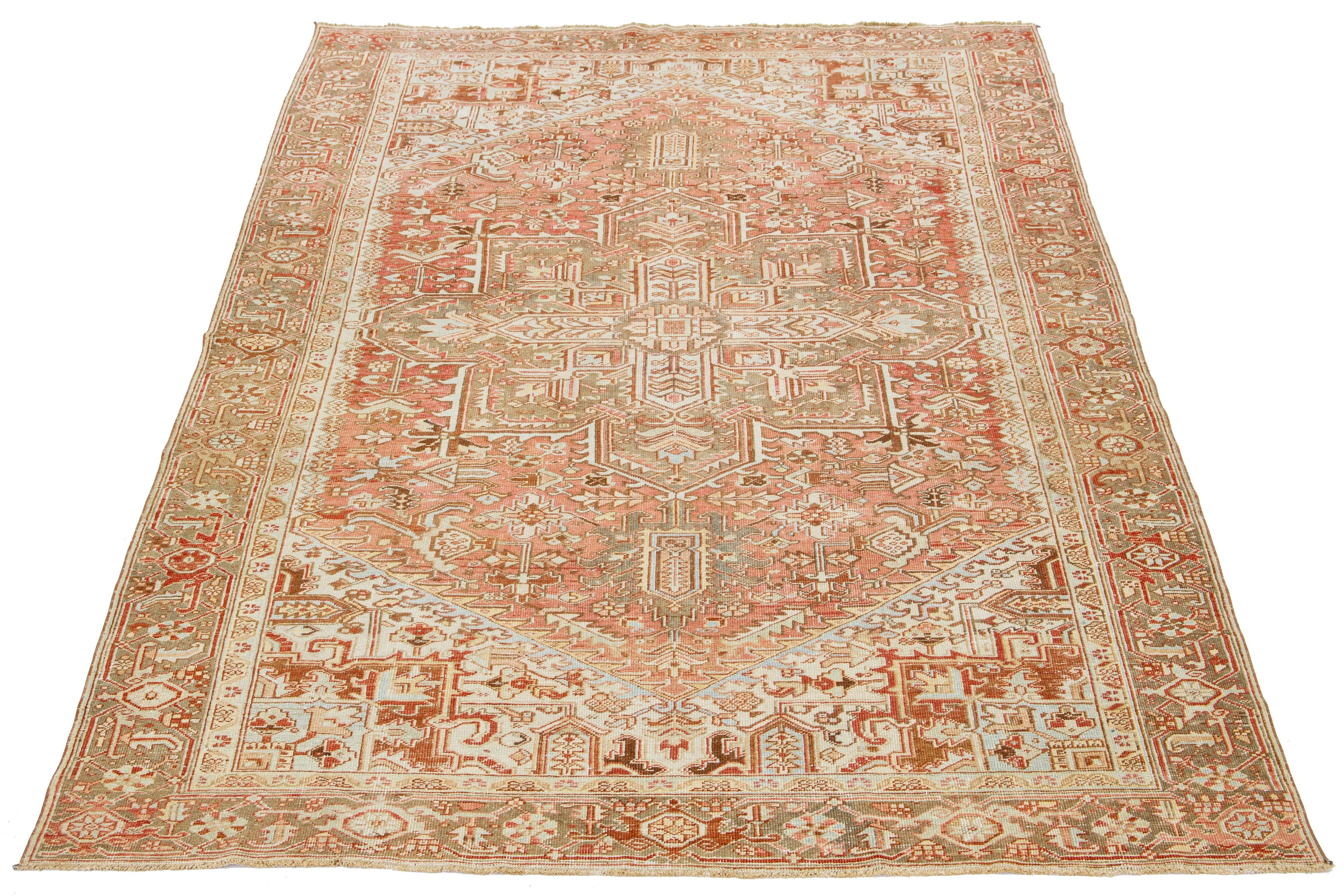 Dieser antike persische Heriz-Teppich ist aus handgeknüpfter Wolle gefertigt. Das rostorangefarbene Feld zeigt ein fesselndes Allover-Muster, das mit Beige-, Pfirsich-, Braun- und Blautönen verziert ist.

Dieser Teppich misst 7'11' x 11'9