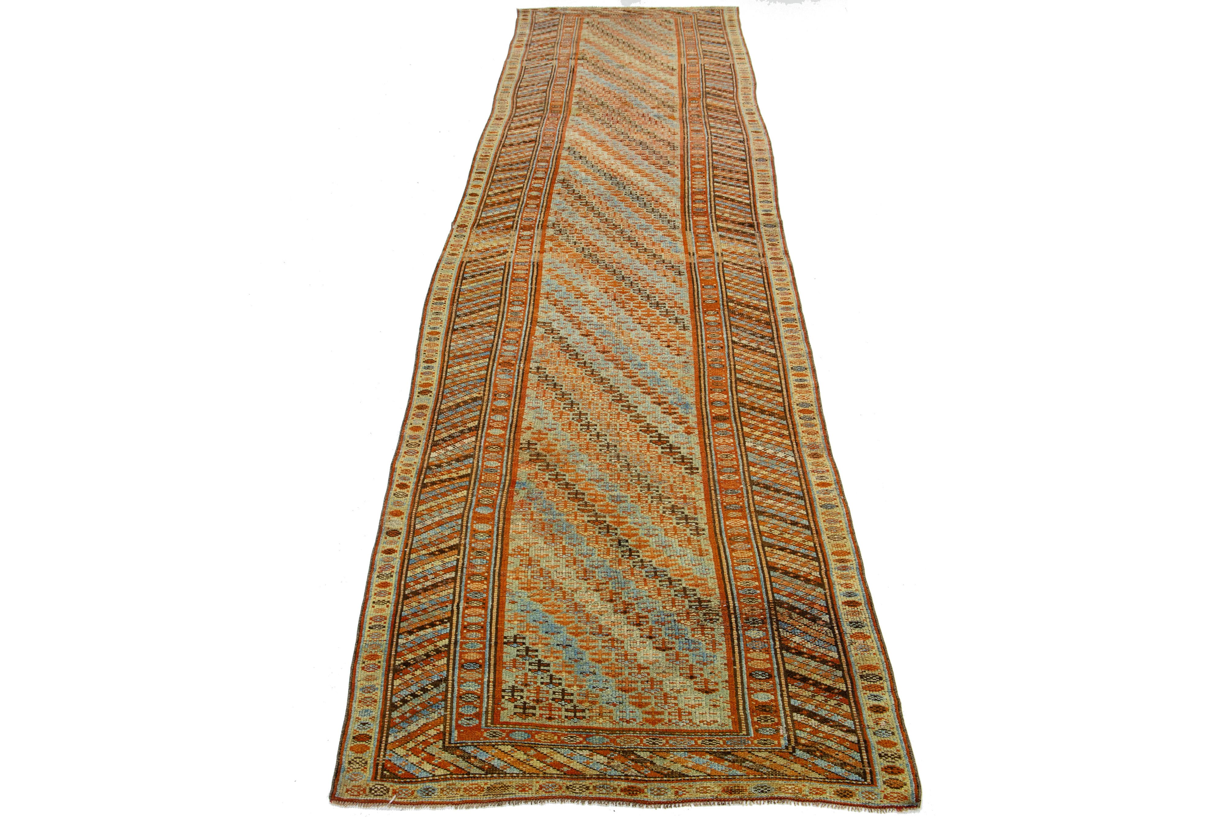 Beautiful Kurdish hand-knotted wool runner with a geometric design on a beige field. Accents of blue, orange, and brown throughout the piece. 

This rug measures 4' x 16'4