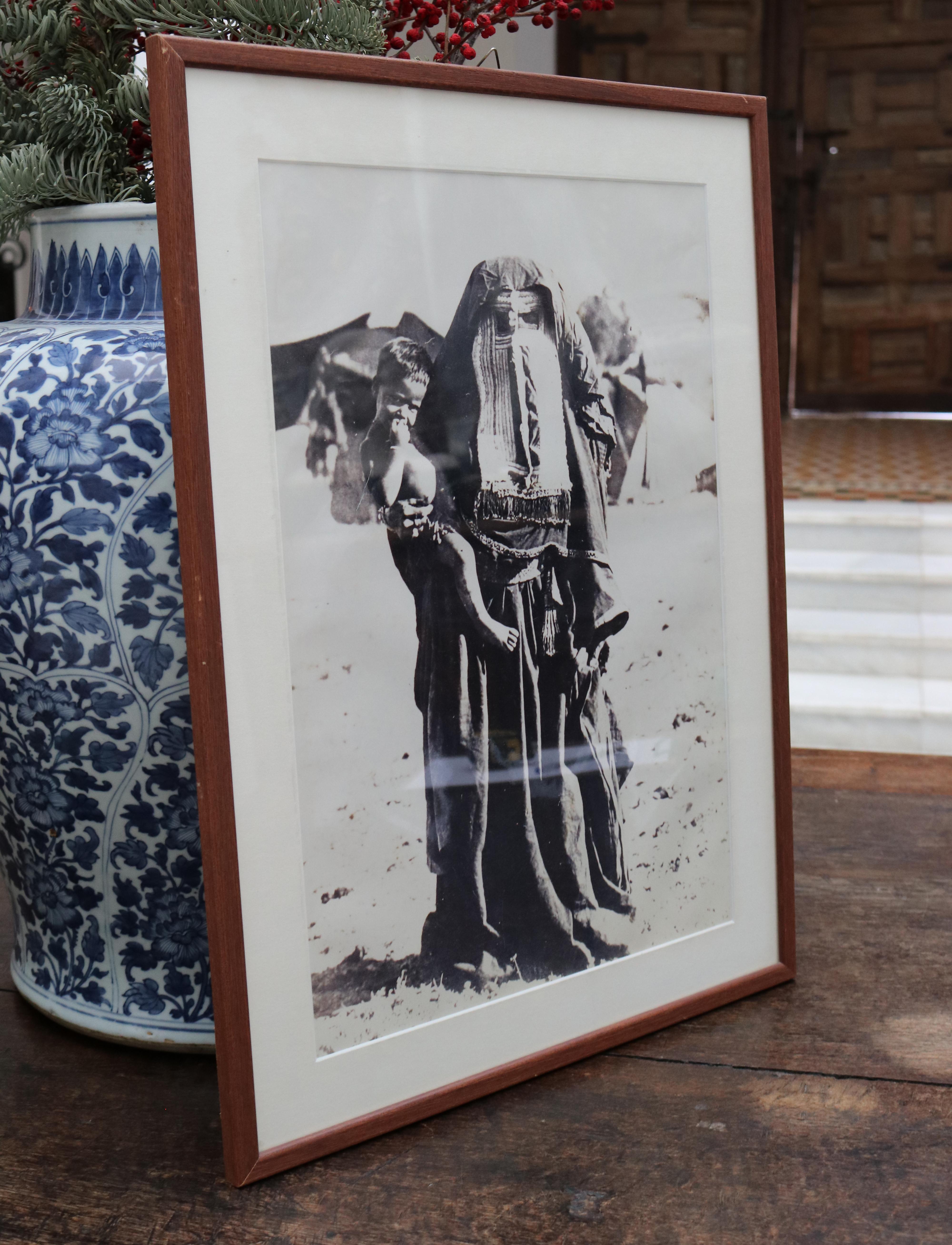 1920s photo of an Arab woman wearing a burqa and holding a child. 

Dimensions with frame: 53 x 39 x 1.5cm.