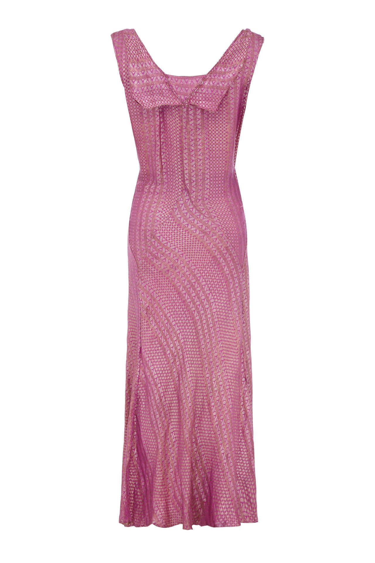 This is a sensational 1920s full-length pink flapper dress. The detail of the fabric is extraordinary, with aztec-style gold and silver woven lamé design would make a memorable choice for a summer party. It features a V-neckline crossing over the