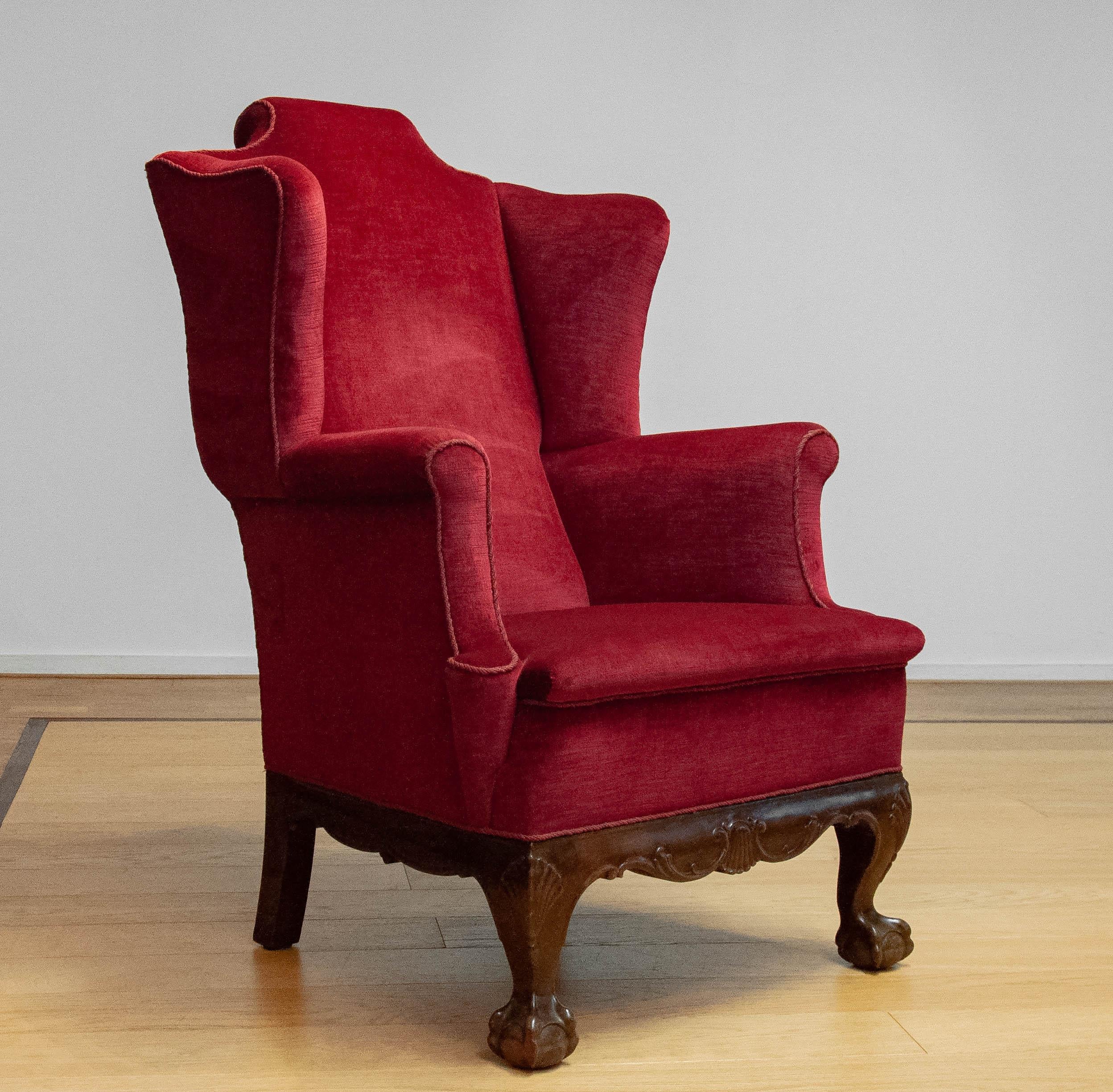 Highly decorative and large red velvet / velours 'Thomas Chappendale style' wingback chair from early 20th century. The red velvet / velours fabric is from a later period and in good and clean condition. The chair sits perfect and supports good.
The