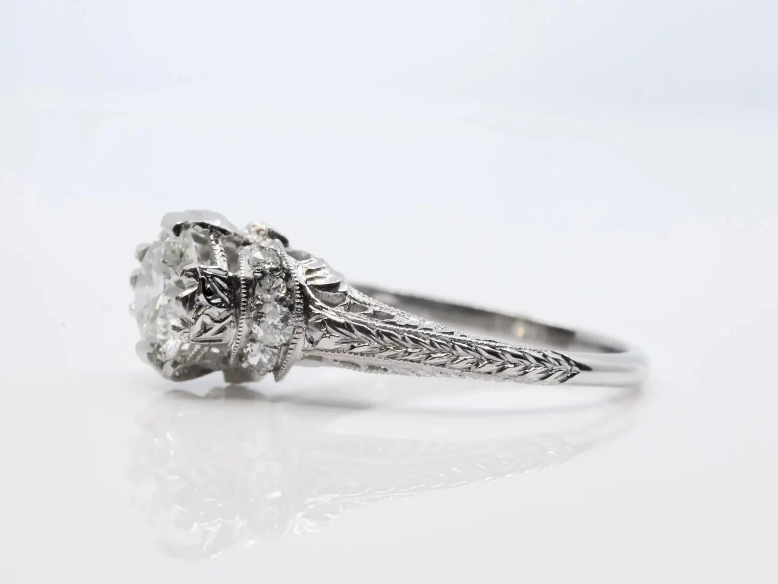 A handmade original Art Deco period diamond solitaire engagement ring in platinum. Centering this one of a kind ring is a 0.75 carat European cut diamond grading as H color and SI clarity. Wrapping around the center diamond are a pair of hand