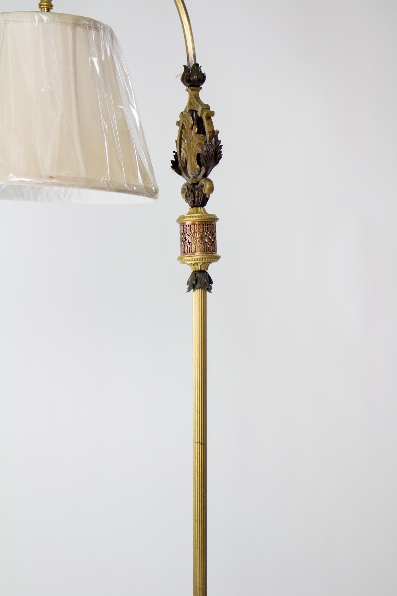 1920’s rococo revival cast iron and brass bridge lamp with shade. Ornate mix of cast iron and brass along the base and stem with foliate patterns. Curved arm holds the shade. American. The shade is new, bell shaped with a Uno fitter in a cream