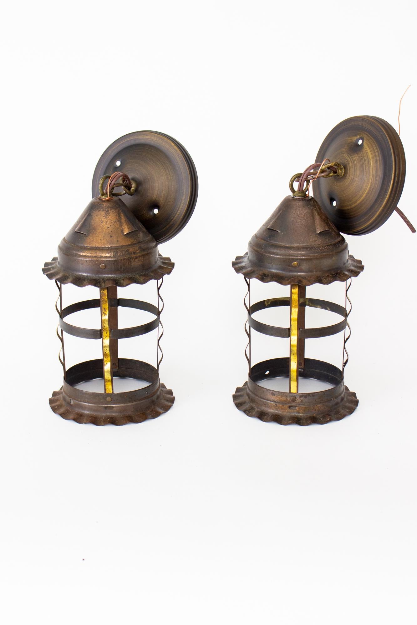 Round metal lanterns. Tudor or revival style, with ruffled edges on the top and bottom of lantern. Side ribs have a bright gilt finish. Originally may have had glass or mica, is currently sold without. Original metal finish has been cleaned and