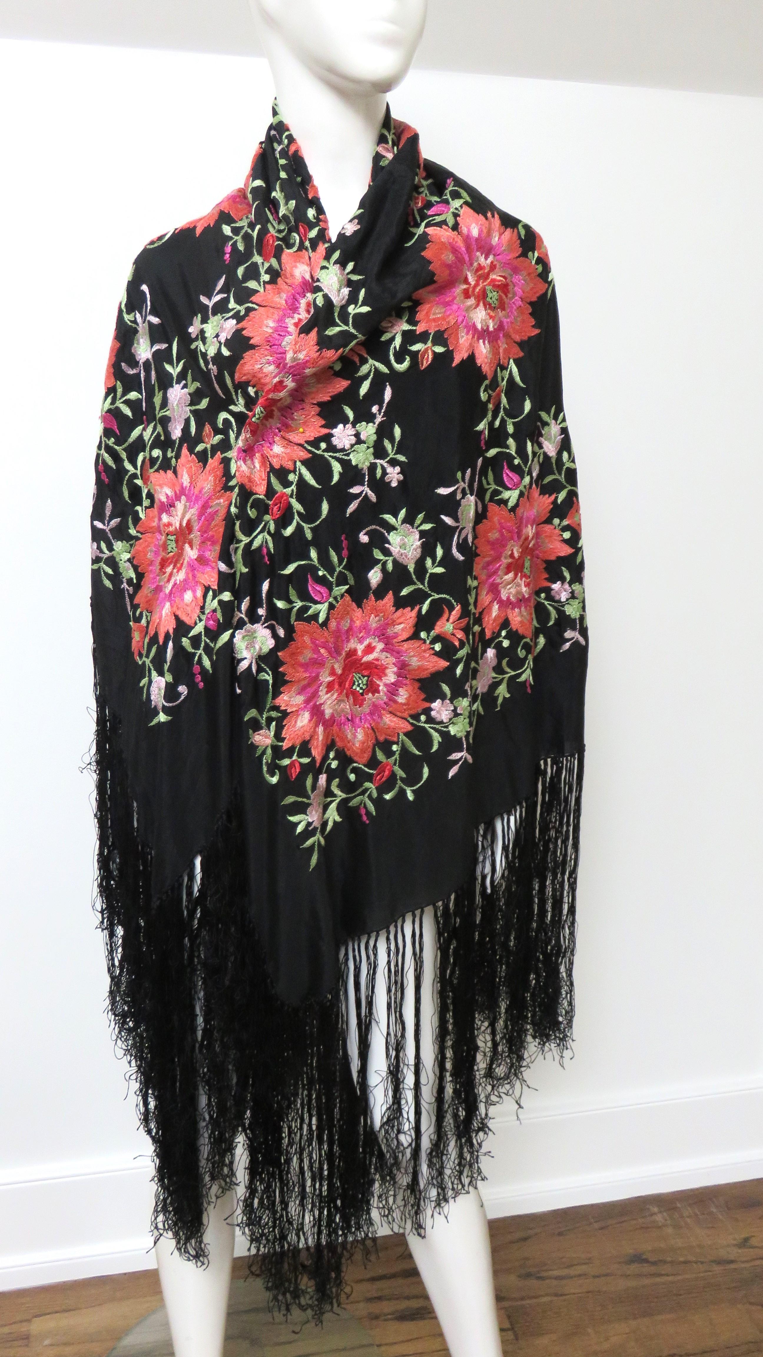 A beautiful flower embroidered 1920s silk piano shawl.  It is comprised of black silk cover in vibrant pink embroidered flowers.  It has 14