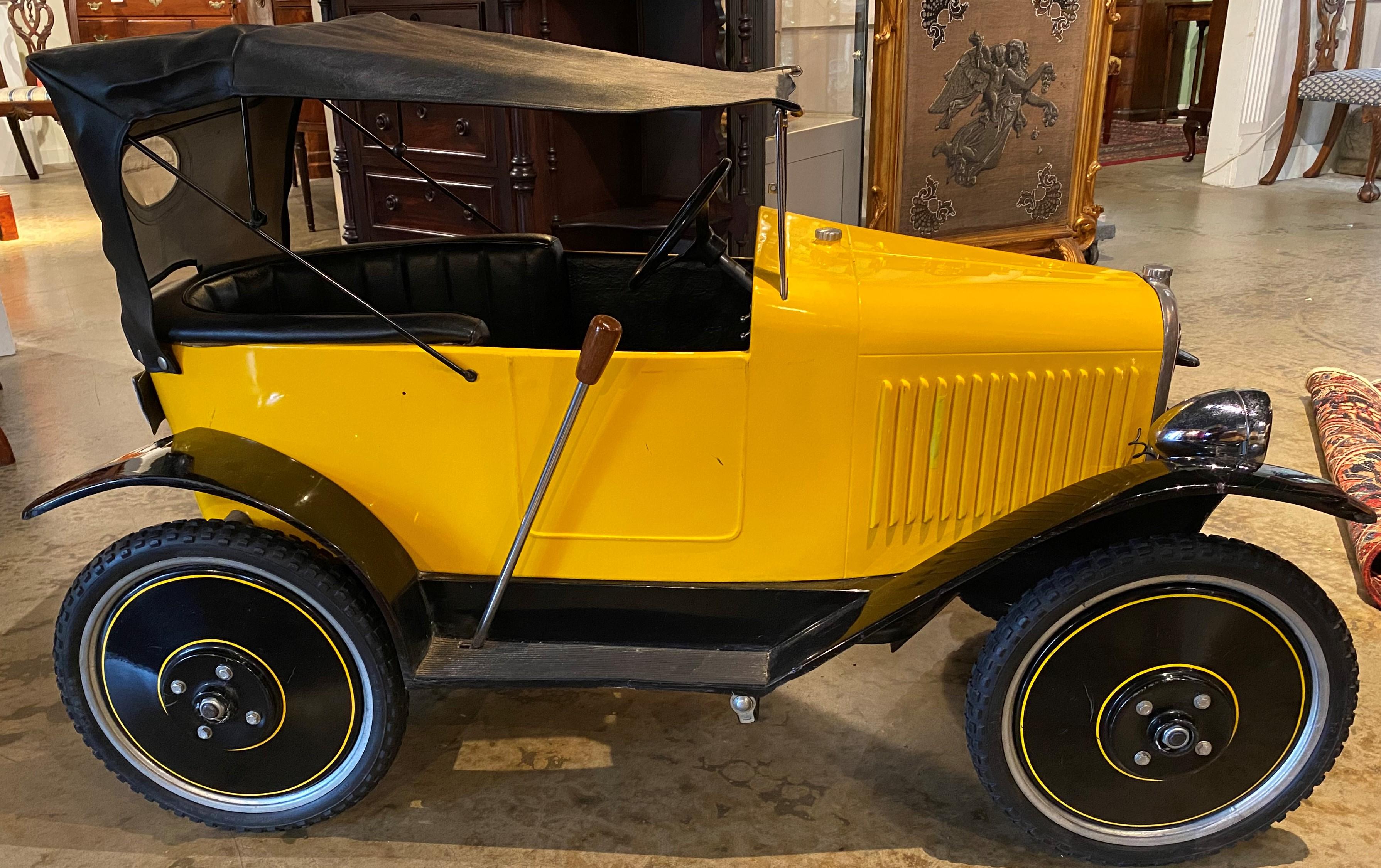 A fine example of a Citroen open seat touring pedal car in yellow and black #65, modeled after the 1920’s Citroen touring car, manufactured by Lely Small Car Co, England, with a badge on the wooden dashboard. This child’s pedal car dates to the