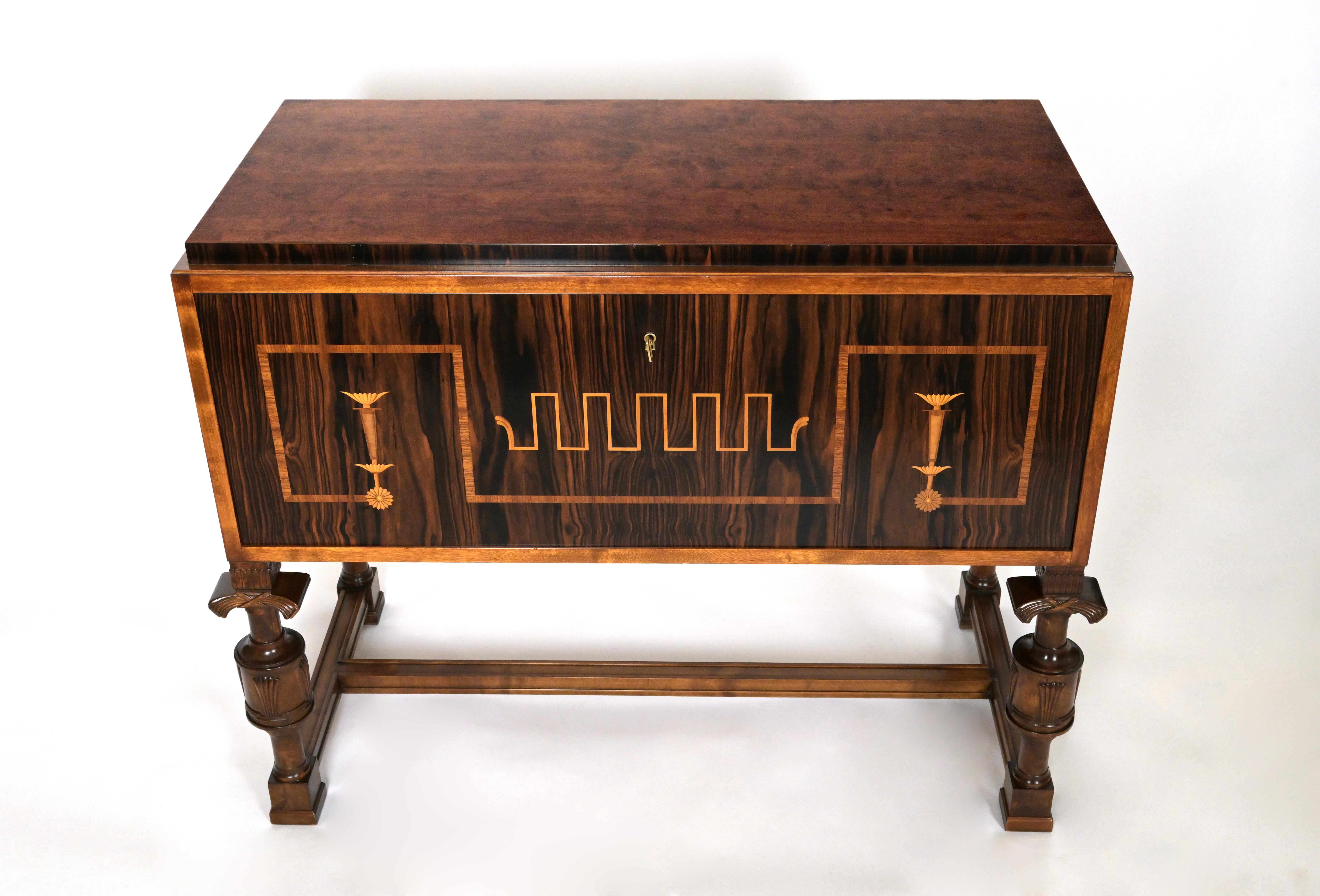A Swedish Grace Period fall front cabinet. The table height surface having rosewood veneer in fall front with stylize geometric marquetry inlaid in figurine contrasting veneer. The base held upon four carved legs in the form of four ballisteries