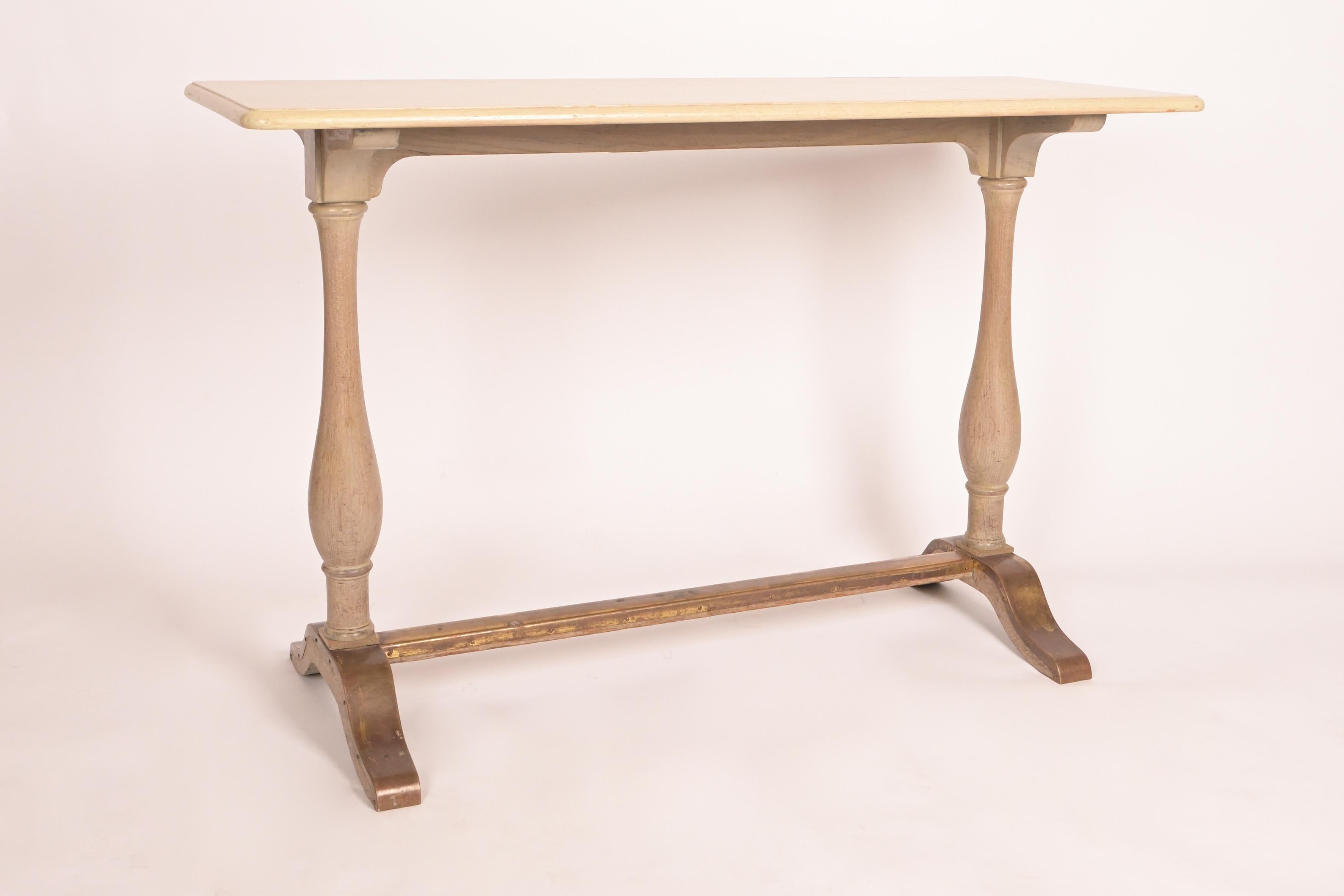 The fine oak rectangular top with rounded corners supported at each end by slender baluster shaped turnings joined by stretcher at base with brass clad feet and stretcher having original patina, the wooden surfaces with a cerused finish. This design