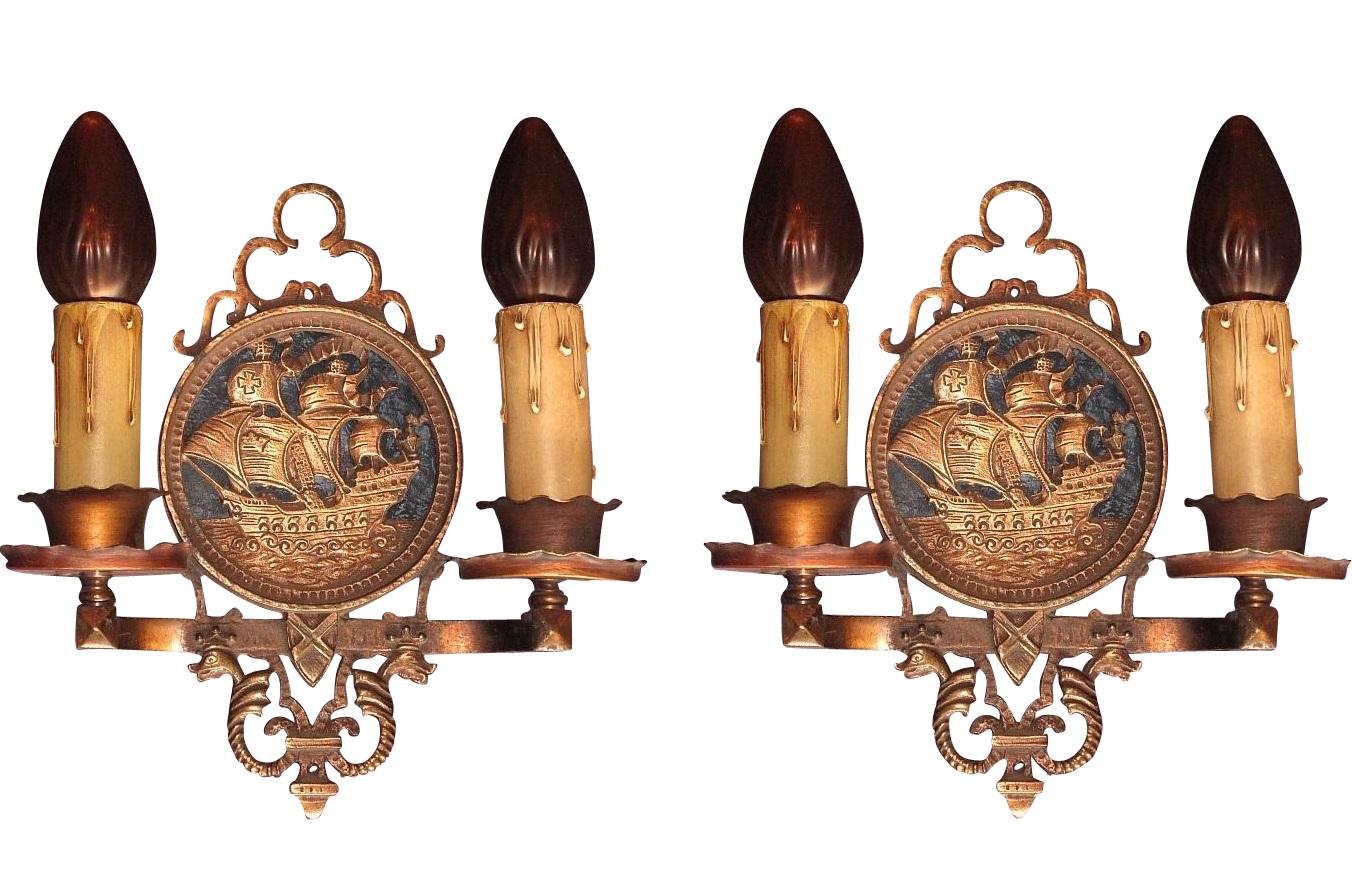 Priced per pair with 2 pair available.
Spanish Galleon in full sail on a calm sea and a blue sky backdrop. 1920s vintage when US design was heavily influenced by European motifs and symbolism. Sconces are solid bronze with most likely brass at the