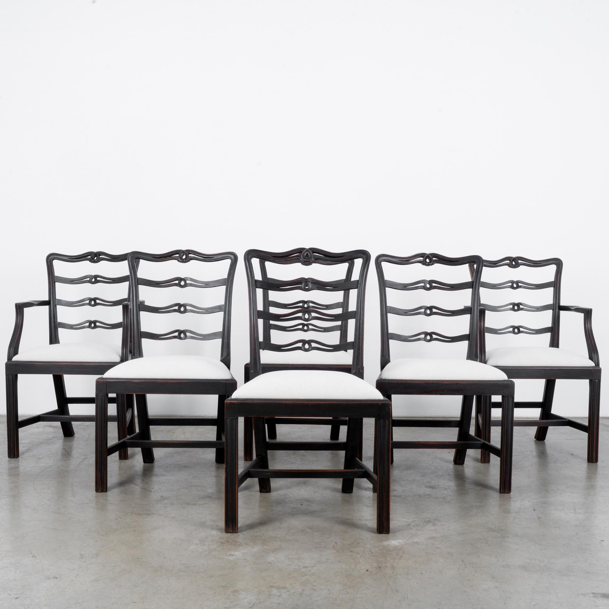 This set of six wooden chairs was made in the United Kingdom, circa 1920. The pure white upholstered seats complement the rich and warm umber shade of the wood. Carved top rails and ridges on the wooden frames show the meticulous craftsmanship
