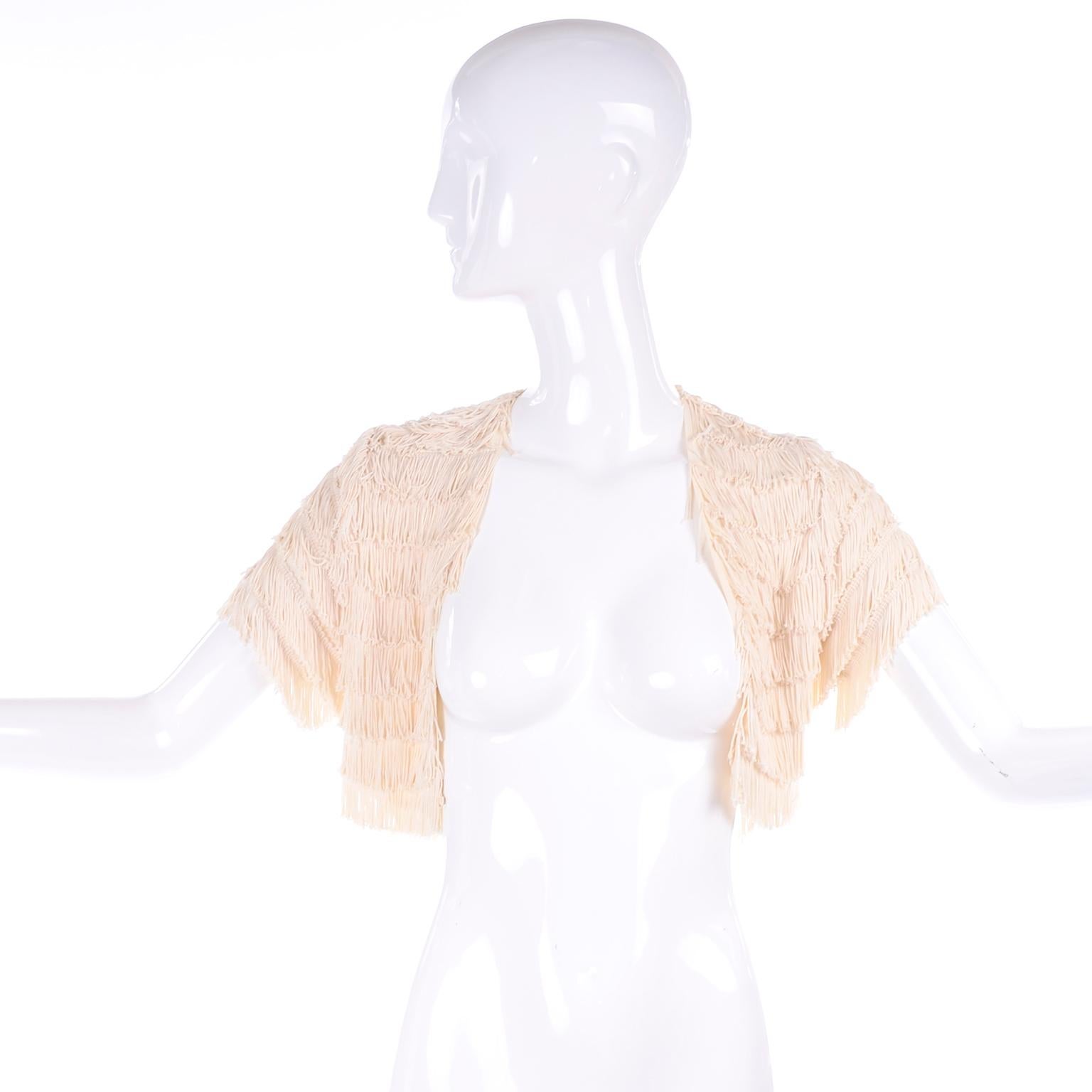 This is a fun and versatile cropped bolero from the late 1920's or early 1920's. This fabulous little top has layers of cream fringe and short sleeves and it is much prettier than the photos represent. It is open in front with no closures and would