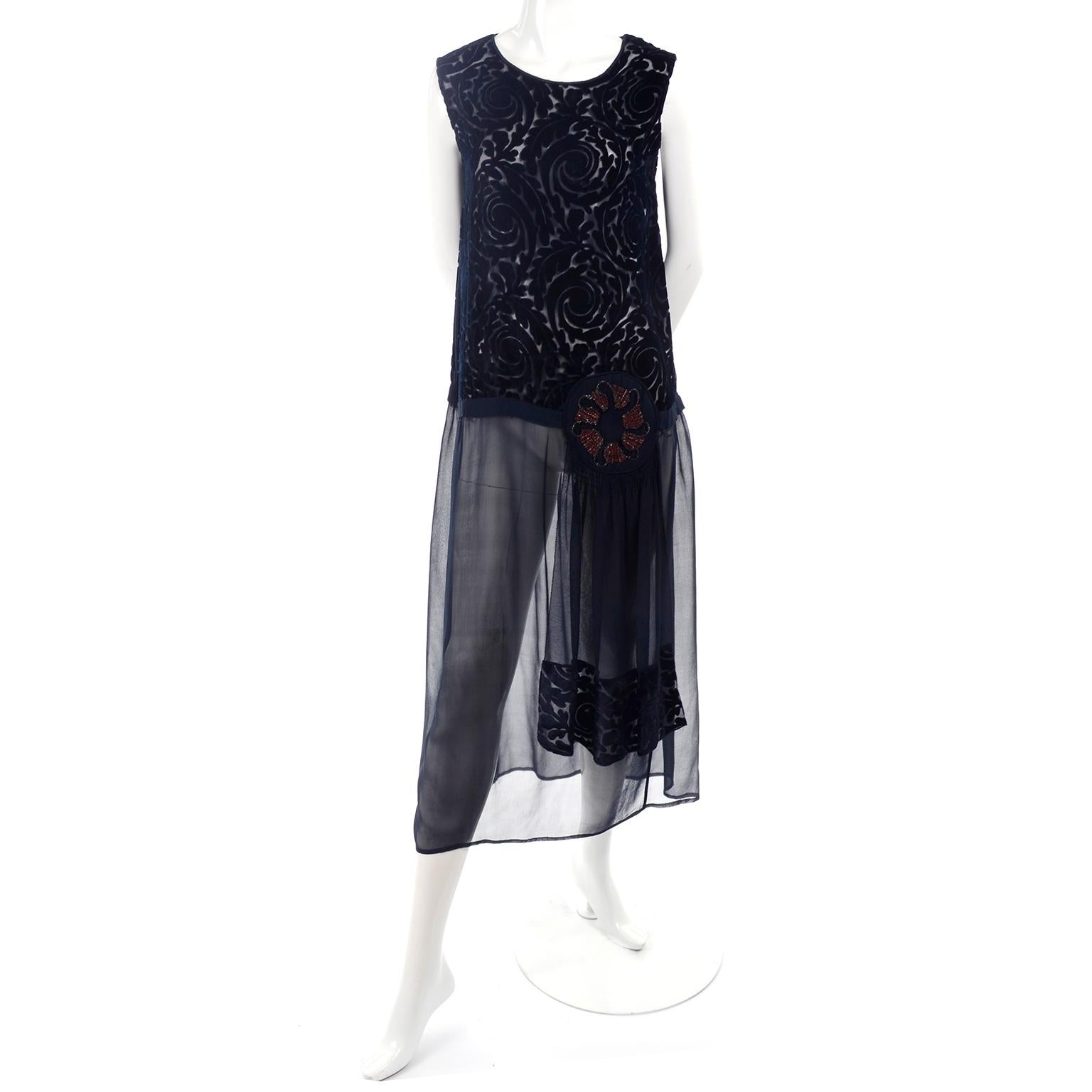 This lovely black 1920's vintage dress has a silk cut velvet bodice and a drop waist that is embellished with a beaded abstract red and gold flower. This fabulous flapper dress has a sheer chiffon skirt and side silk panels. These dresses are meant