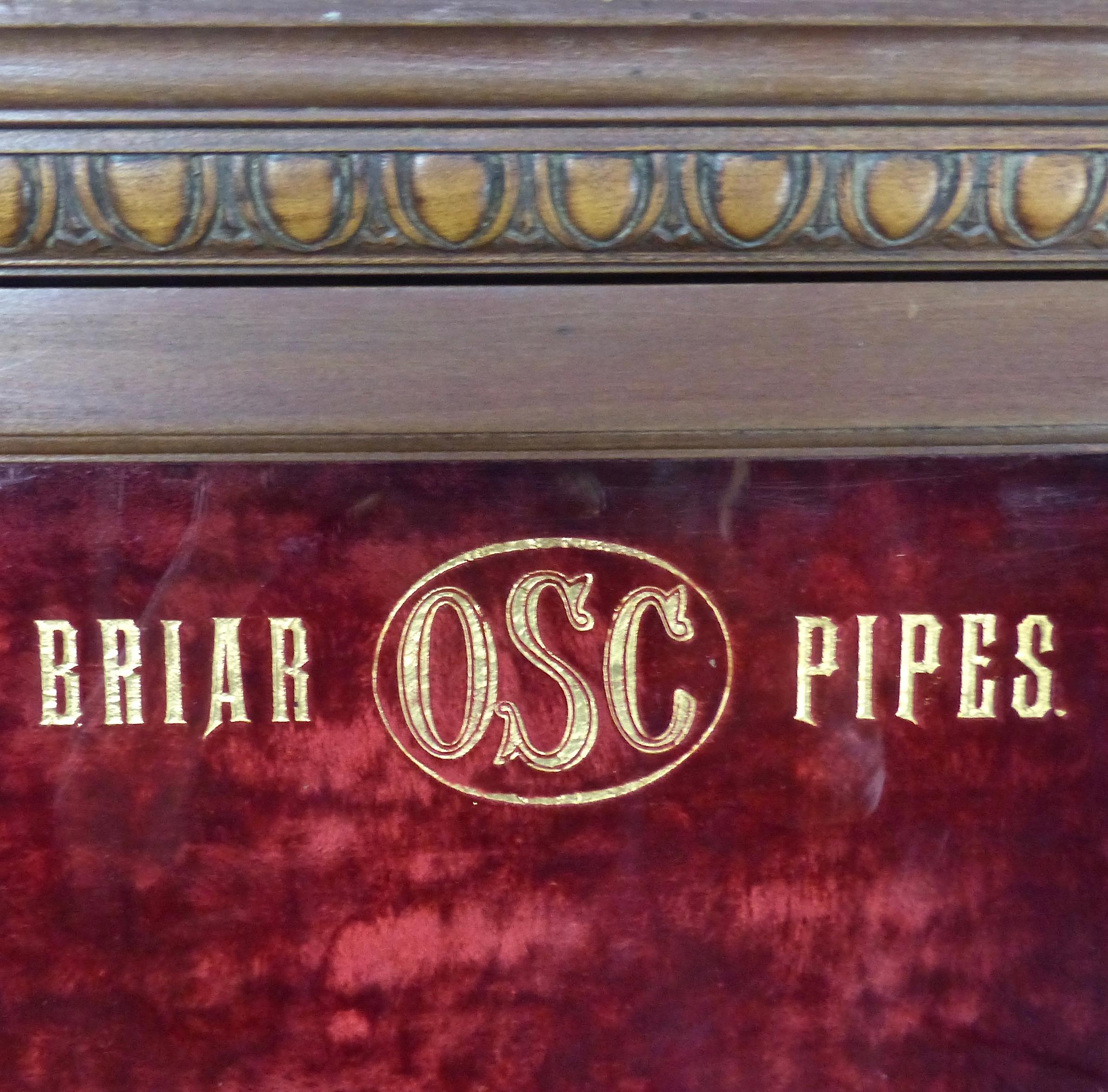 A wooden, wall-mounted display case for Briar OSC Pipes. The circa 1920s cabinet features hand carved details in its frame; original brass hardware; and the piece-de-resistance — a crushed red velvet backing. Ready for your man cave!
Dimensions: