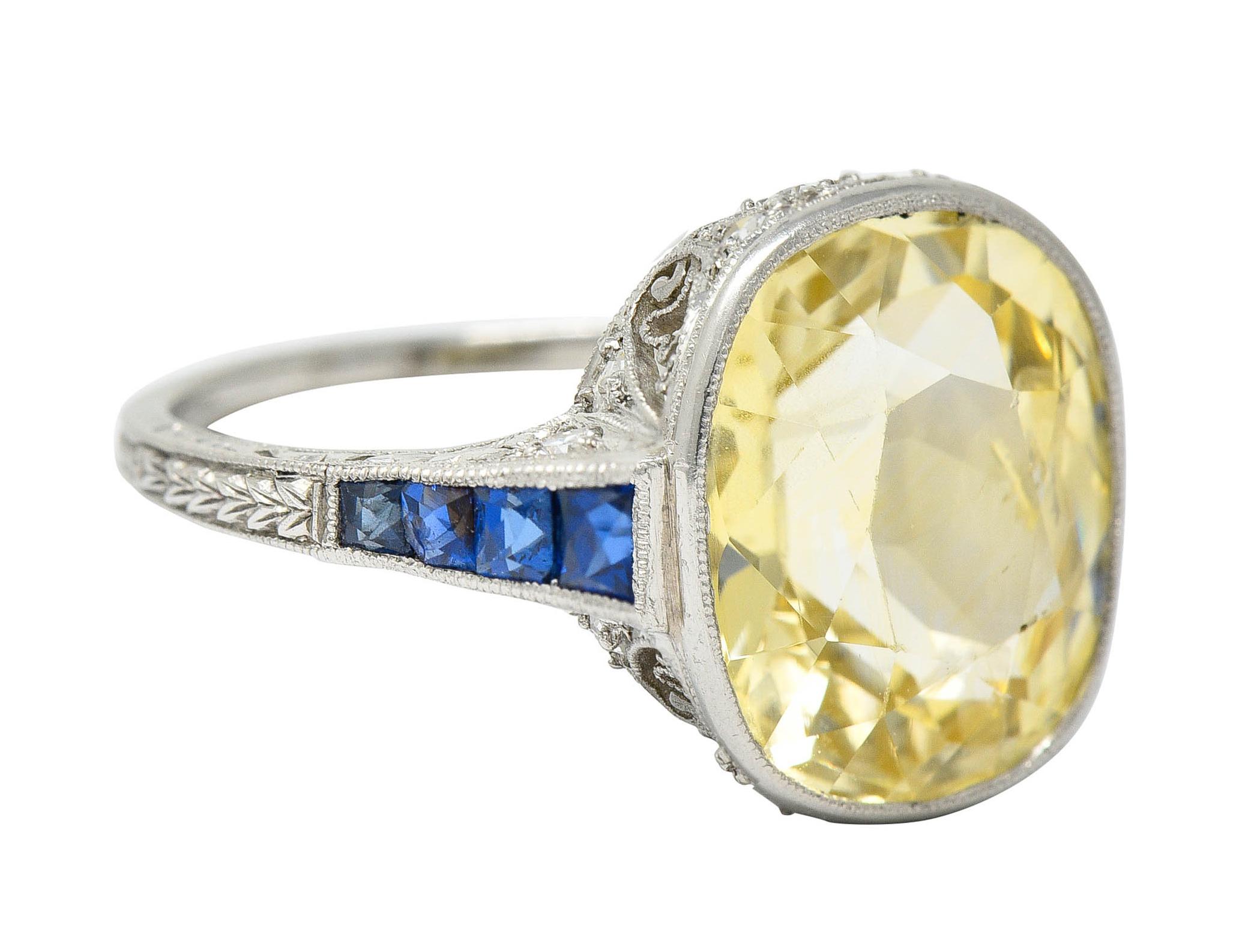 Centering a mixed cushion cut light yellow sapphire weighing approximately 7.50 carats

Bezel set in an ornate mounting with a stylized heart motif gallery and engraved foliate shoulders

Accented throughout by single and transitional cut diamonds