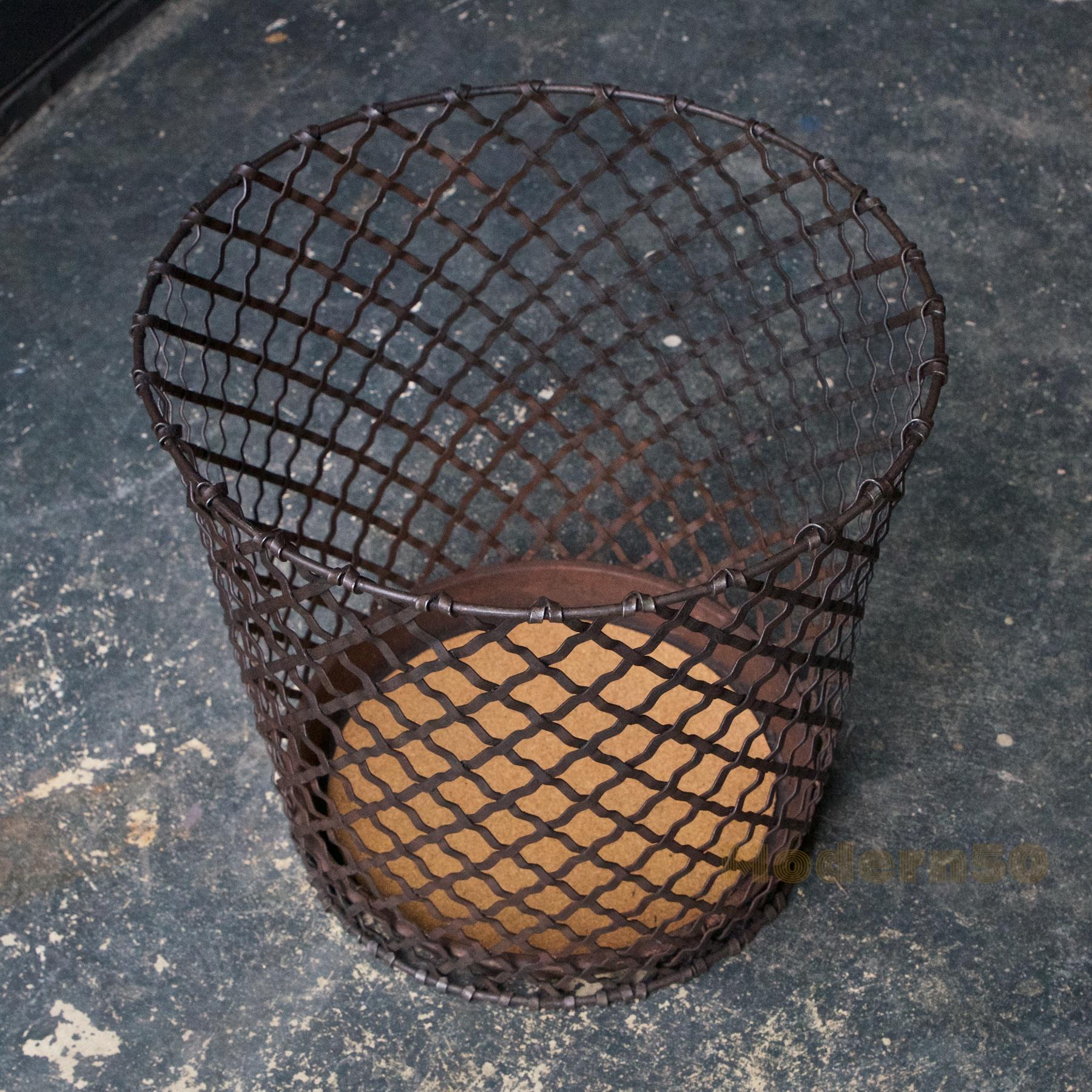 A wonderful American Industrial Age relic. A woven steel lattice trash can, no makers markings. We have Inlayed a new cork bottom to seal the metal bottom, which has some holes from rust, but remains structurally sound.