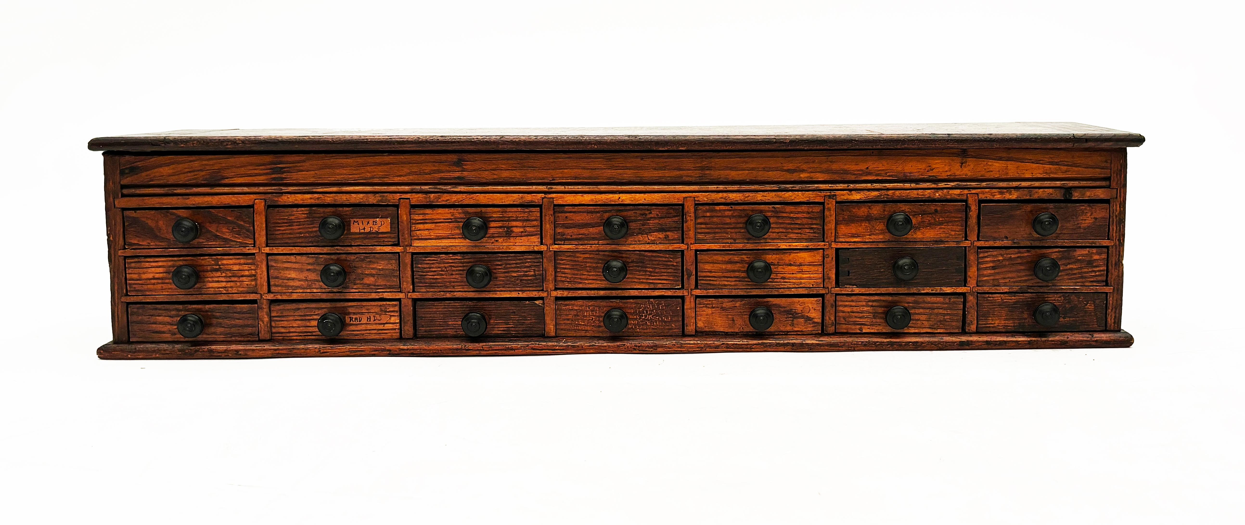 This magnificent piece was once used by a master watchmaker. This uniquely sized cabinet would have sat upon a larger wooden work bench and housed small watch parts of that era. Made of rich tiger oak, the original surface is still wholly intact