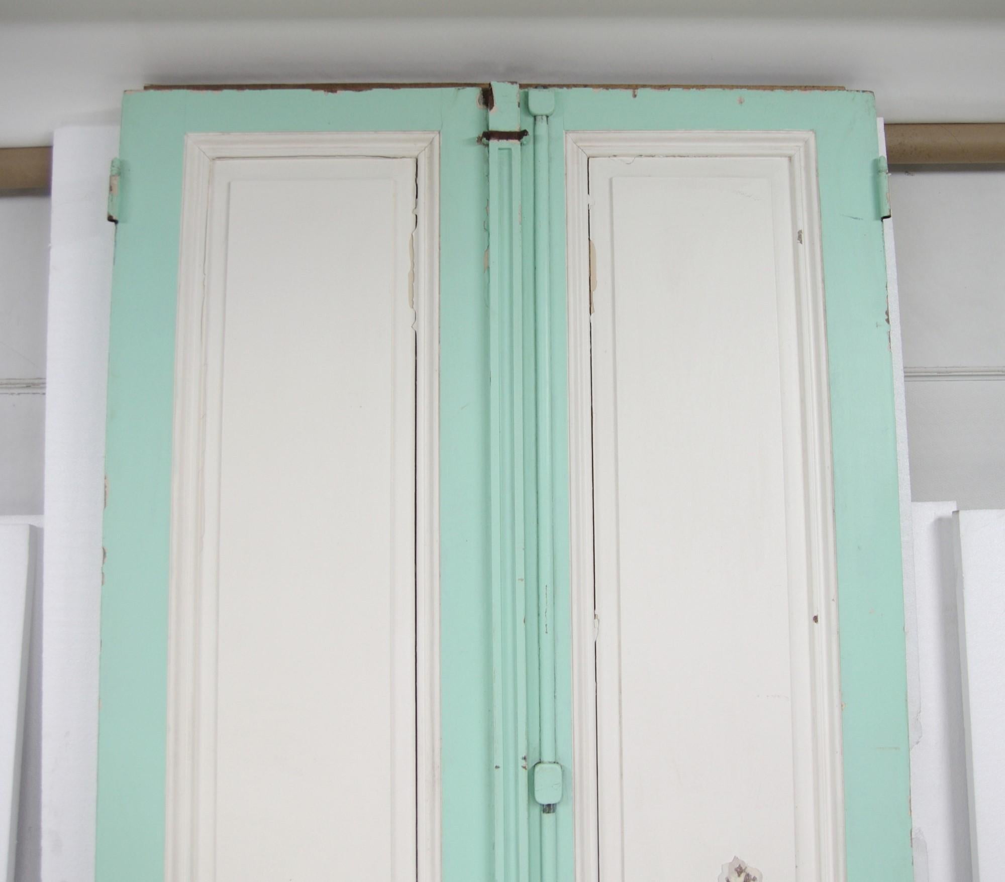 1920's set of tall painted wood parlor doors complete with original cremone bolts. They are from Buenos Aires and are painted white and green on each side and are possibly Spanish Cedar. Priced as a double. This can be seen at our 400 Gilligan St