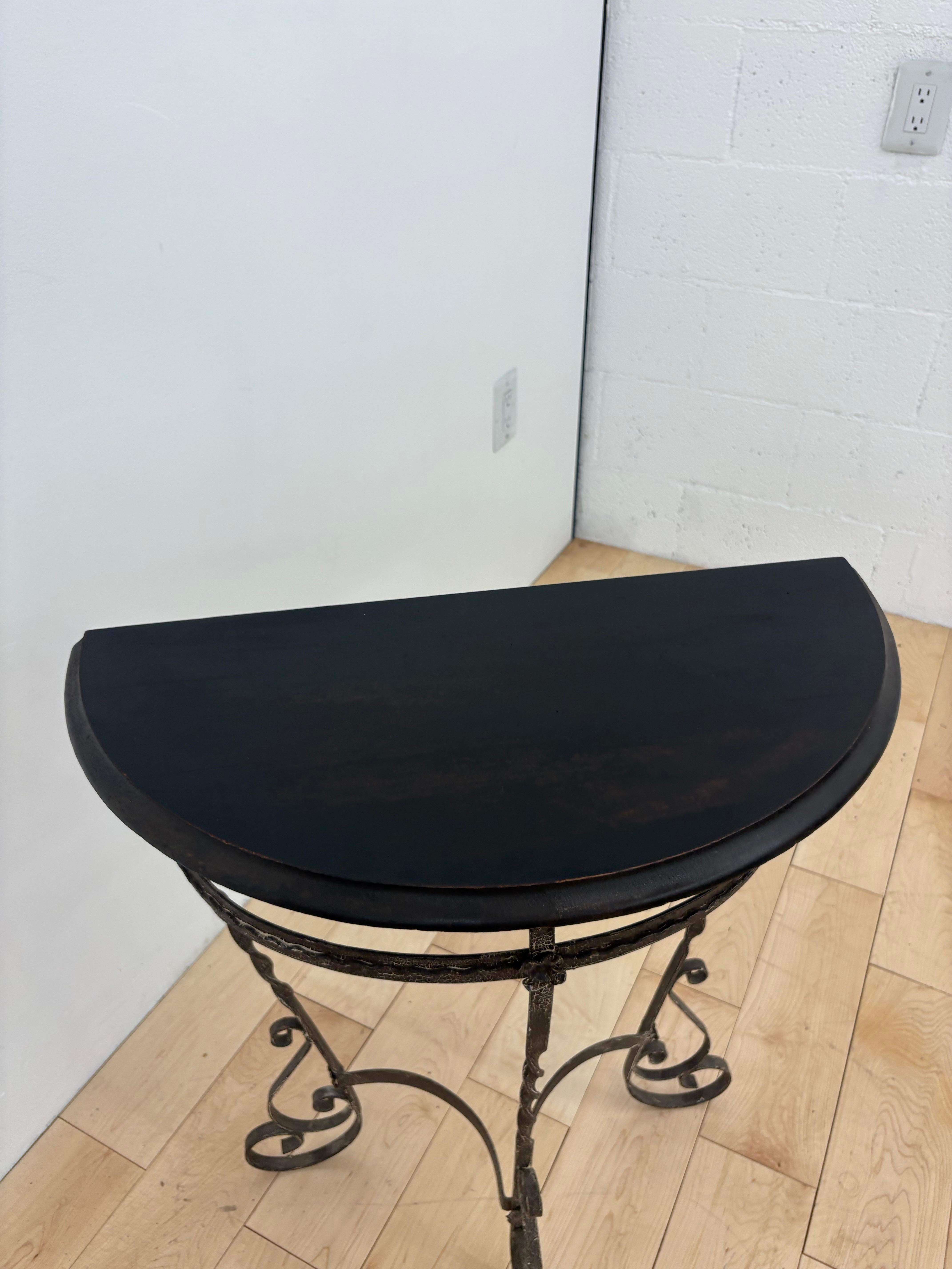 Antica consolle demi-lune degli anni '20 con una base in ferro battuto forgiato a mano con intricati dettagli floreali e a volute e un ricco piano a mezzaluna in mogano. Questo tavolo d'ingresso vintage fonde gli stili dell'Art Nouveau francese e