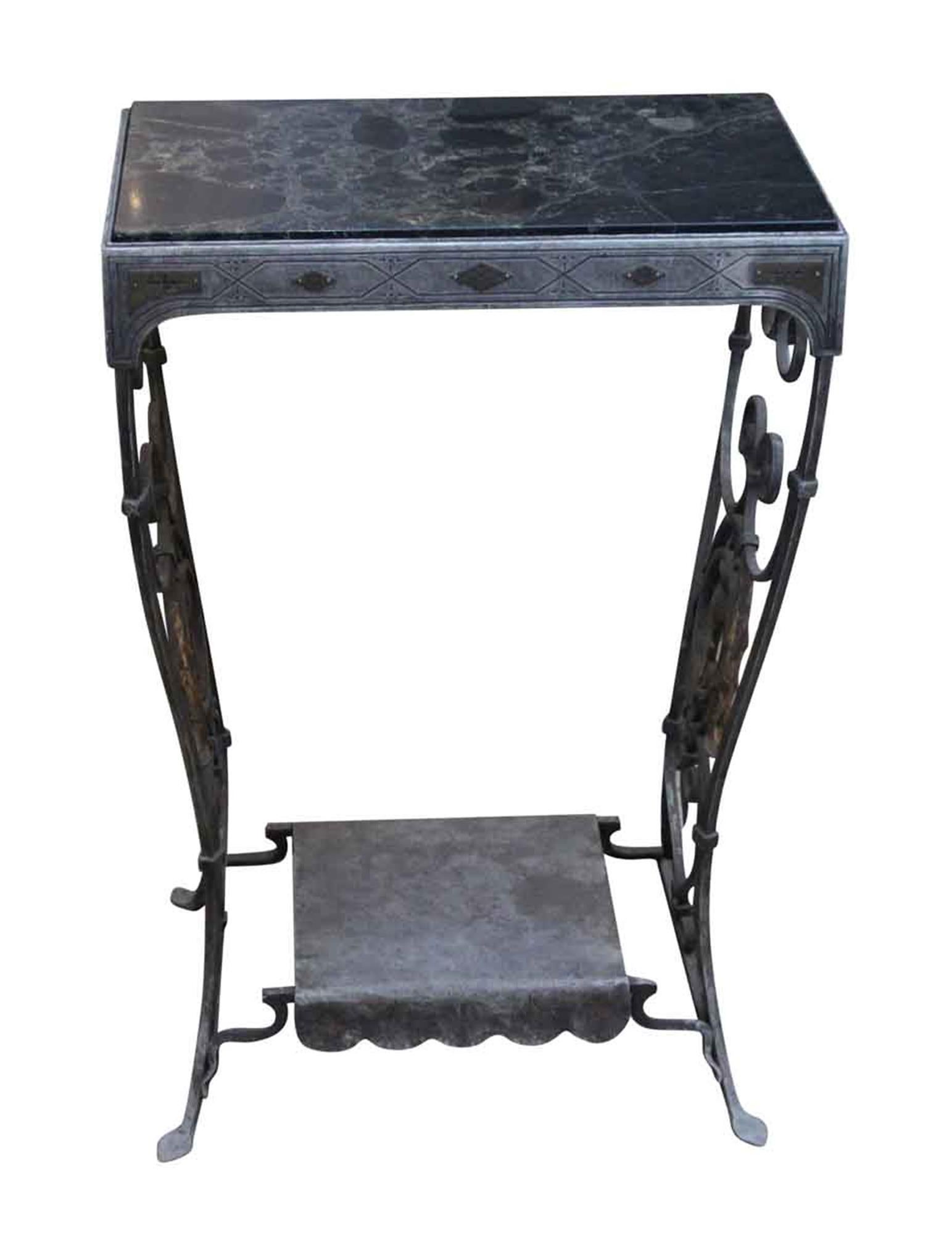 1920s wrought iron table with decorative details and a black and gray marble top. This can be seen at our 5 East 16th street location on Union Square in Manhattan.